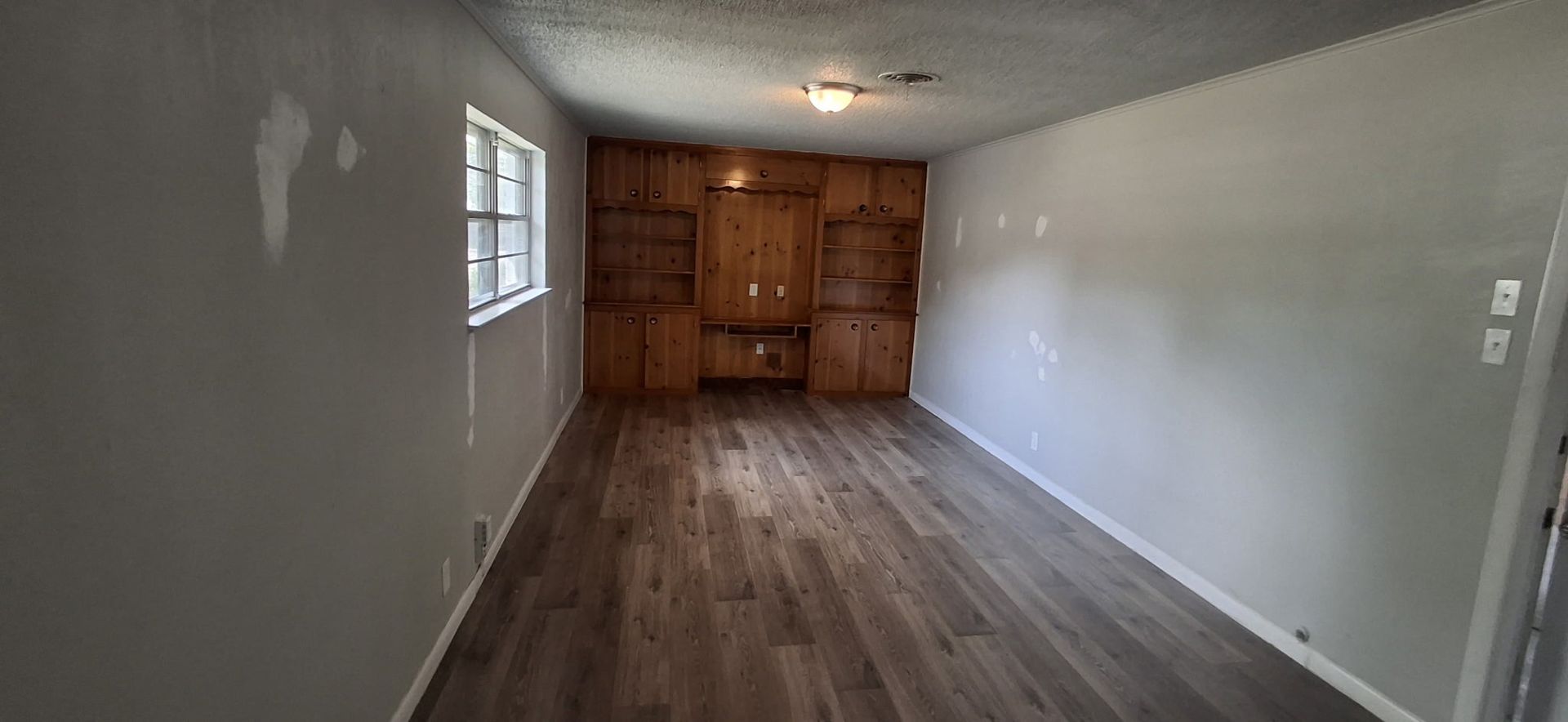 Interior of a room with hardwood floors, white walls, and built-in wooden shelving.