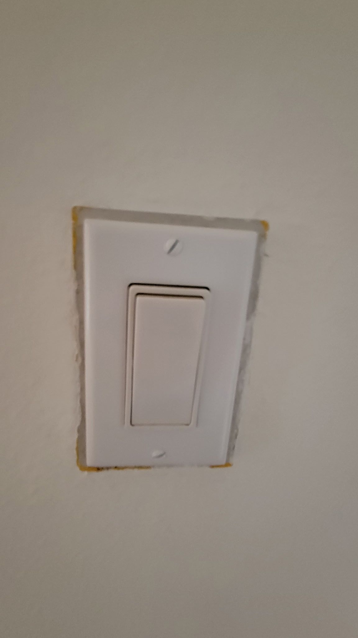 White light switch in a wall, slightly off-center.