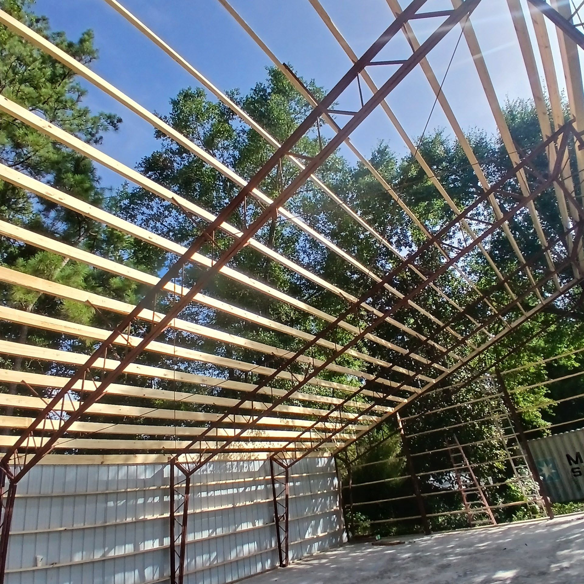 Unfinished building frame with wooden beams and brown metal supports, blue sky in the background.