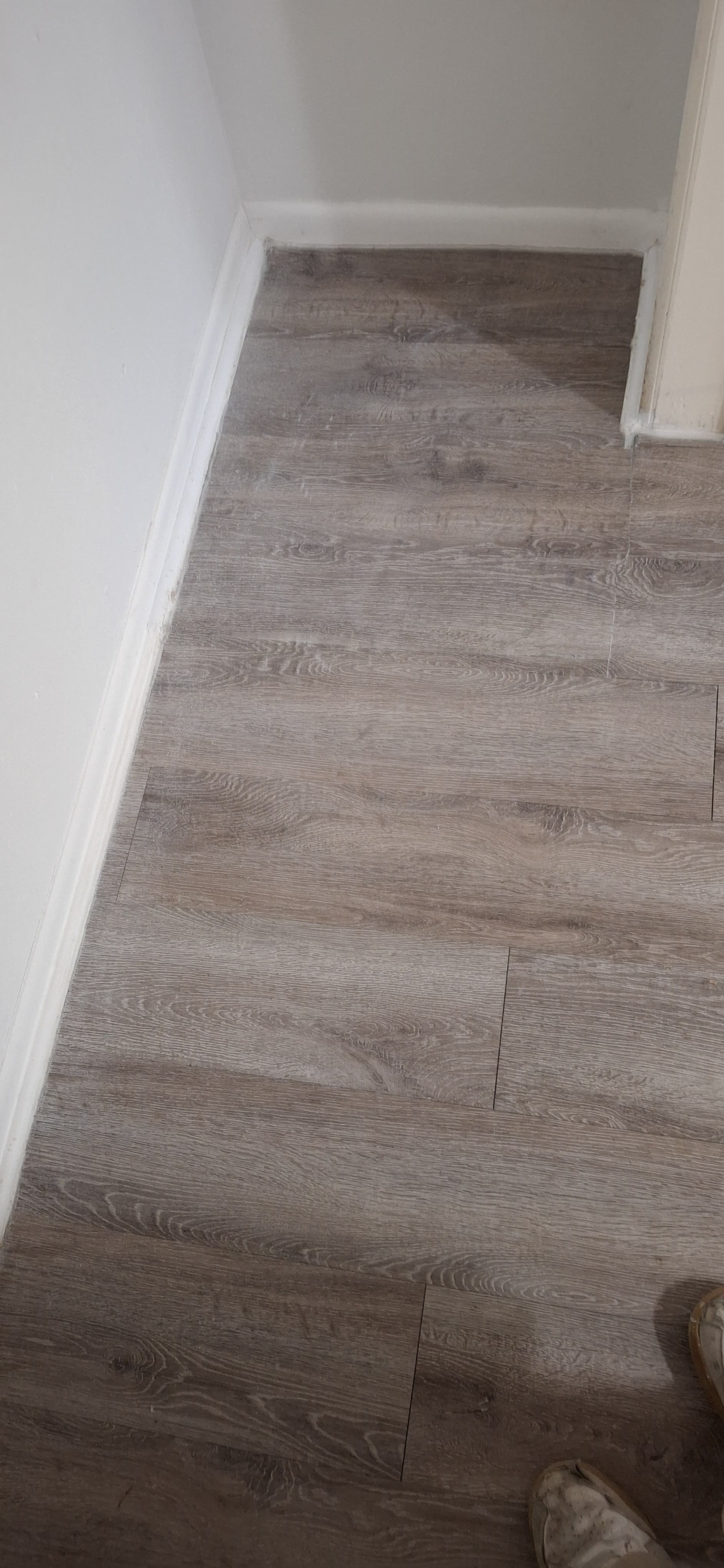 Brown wood-look flooring along white walls with baseboards.
