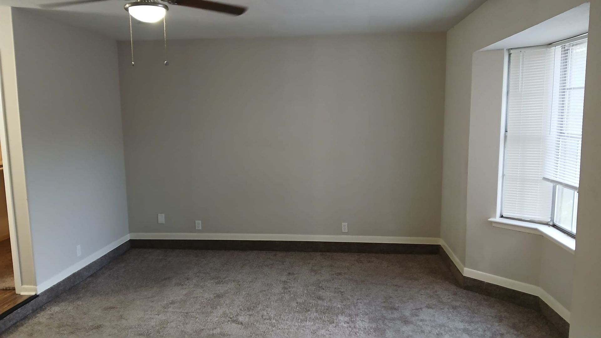 Empty room with neutral walls, carpet, and a window.