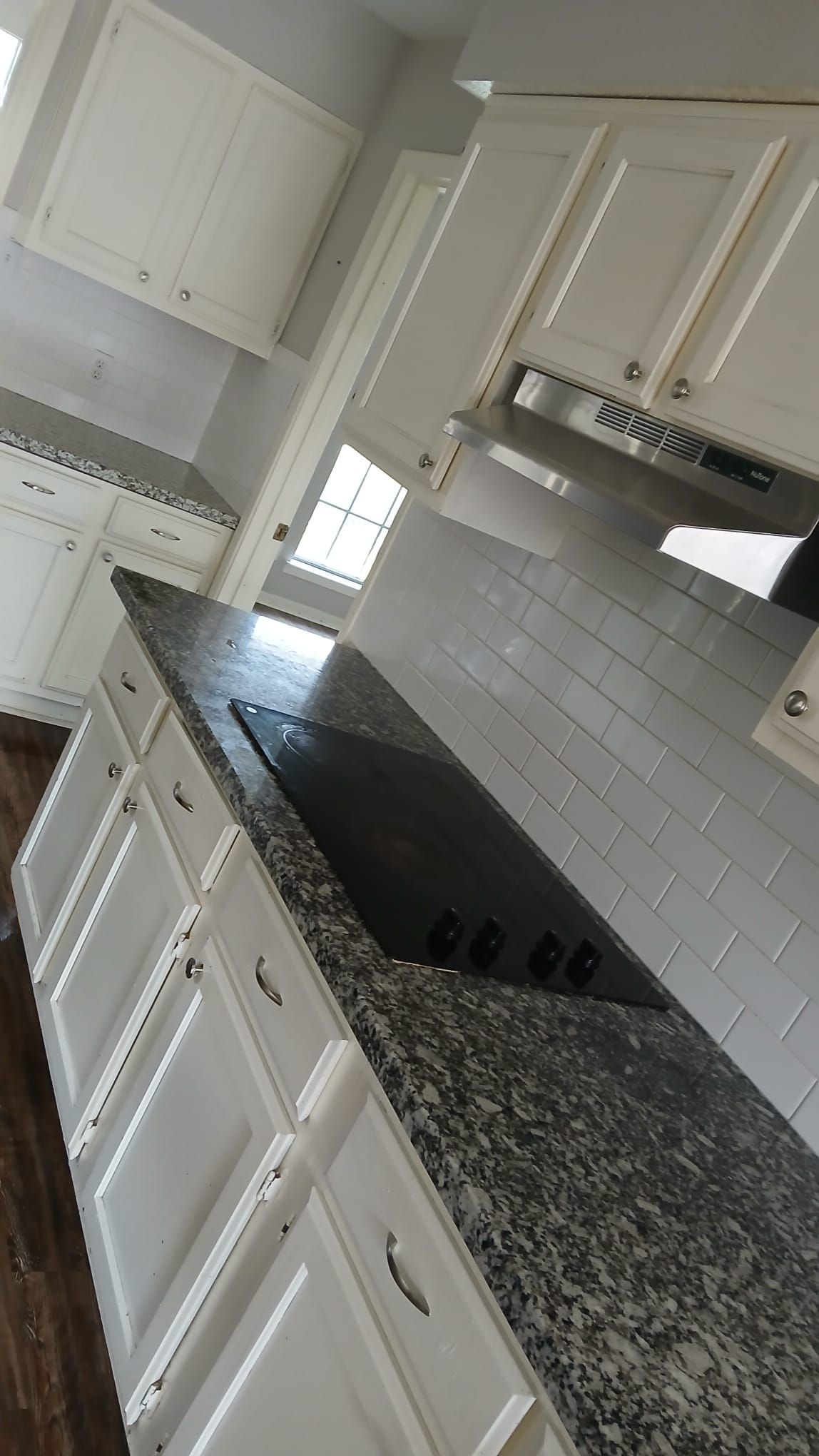 Kitchen with white cabinets, dark granite countertop, and subway tile backsplash.