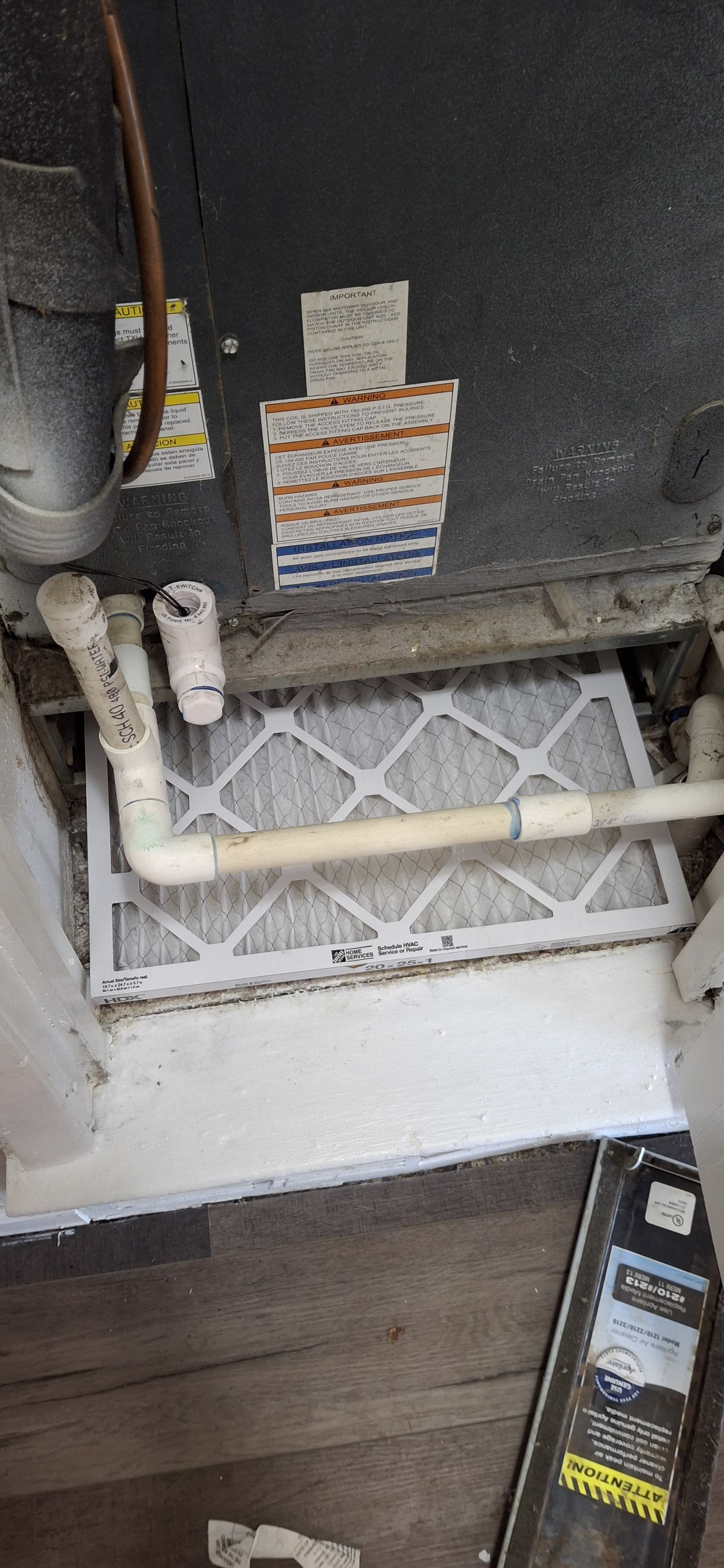 Furnace air filter. Filter is dirty, next to PVC piping and a new filter. Gray and white.