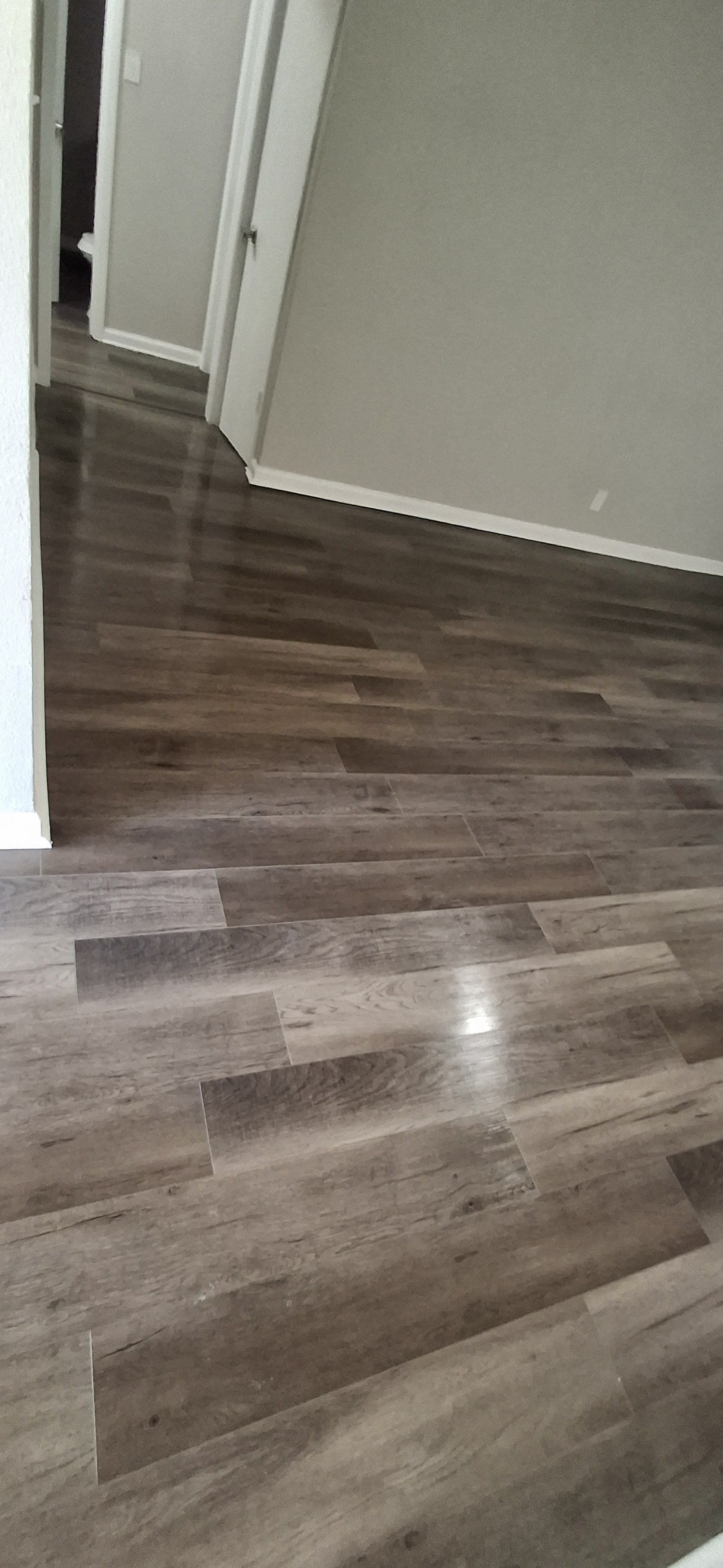 Laminate flooring in a room with light gray walls, angled view.
