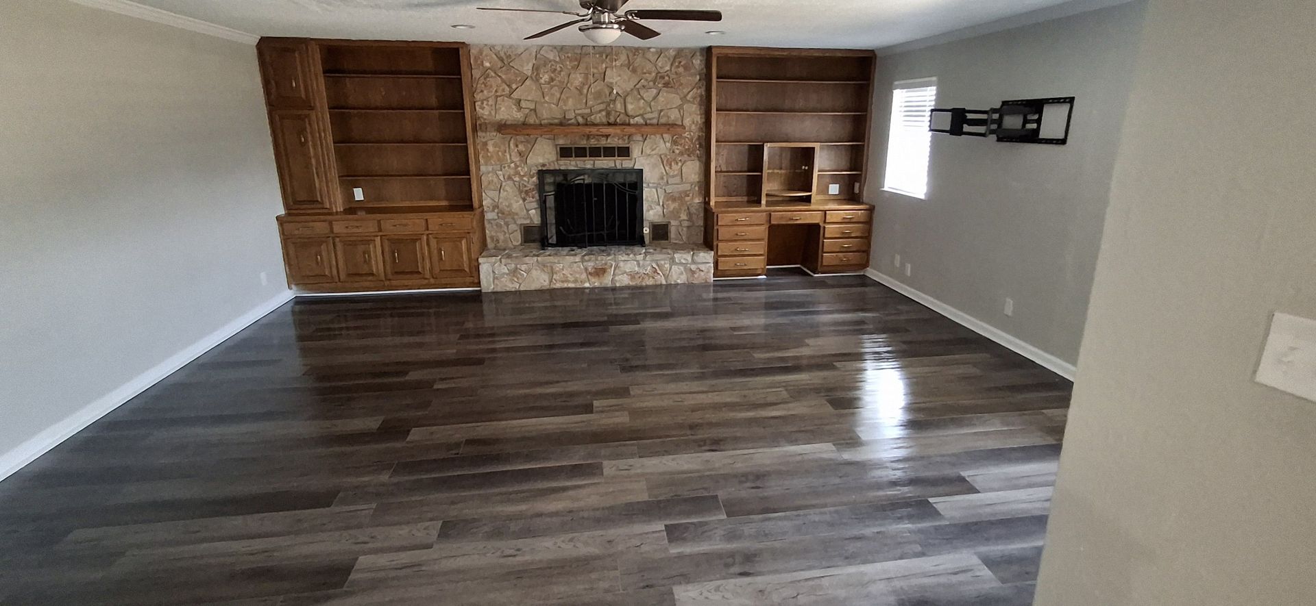 Living room with fireplace, built-in shelves, wood floors, and neutral walls.