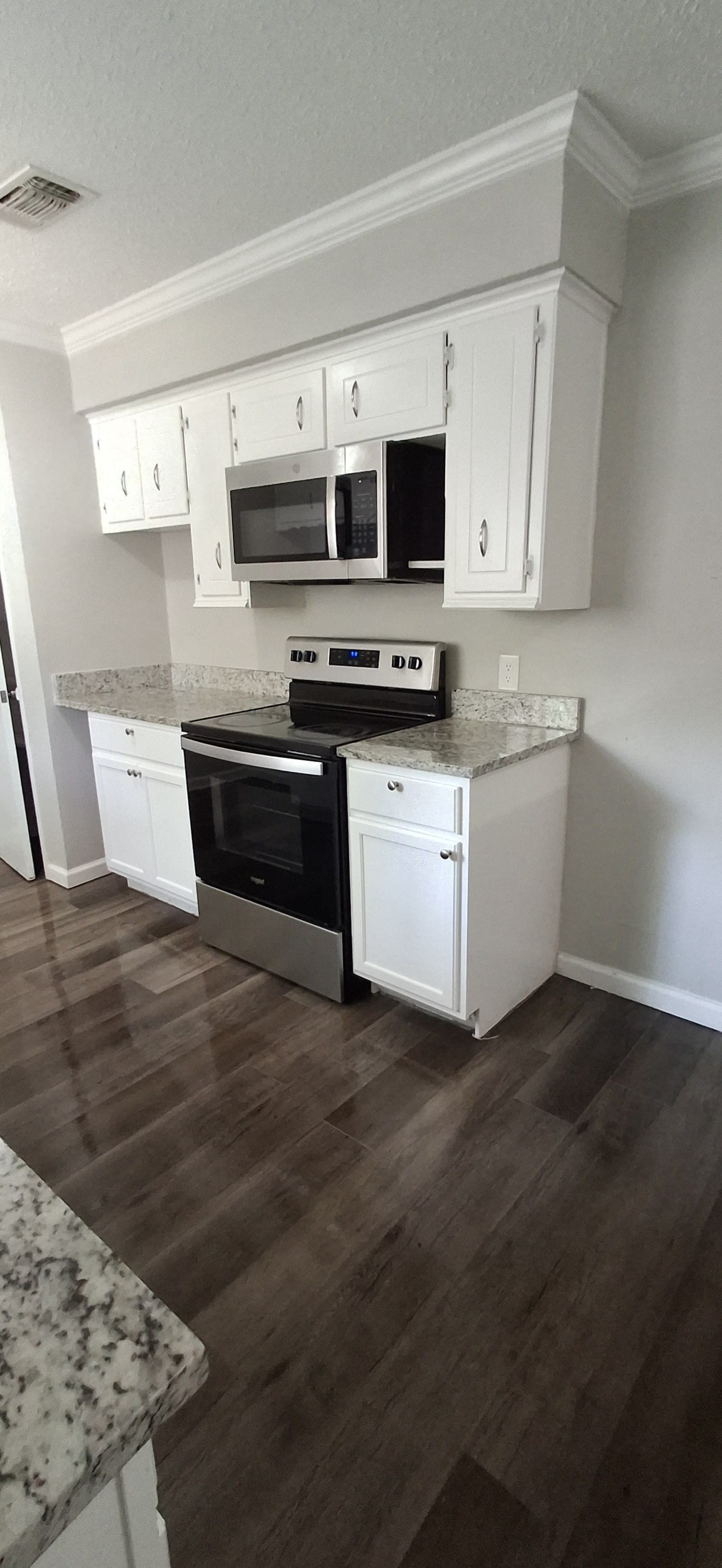Kitchen with white cabinets, stainless steel appliances, and dark wood flooring.