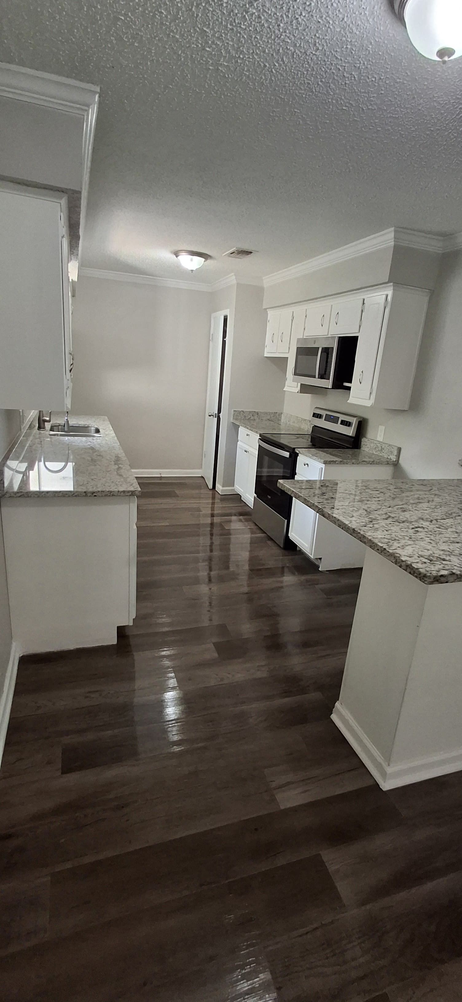 Kitchen with white cabinets, dark wood floors, and granite countertops.