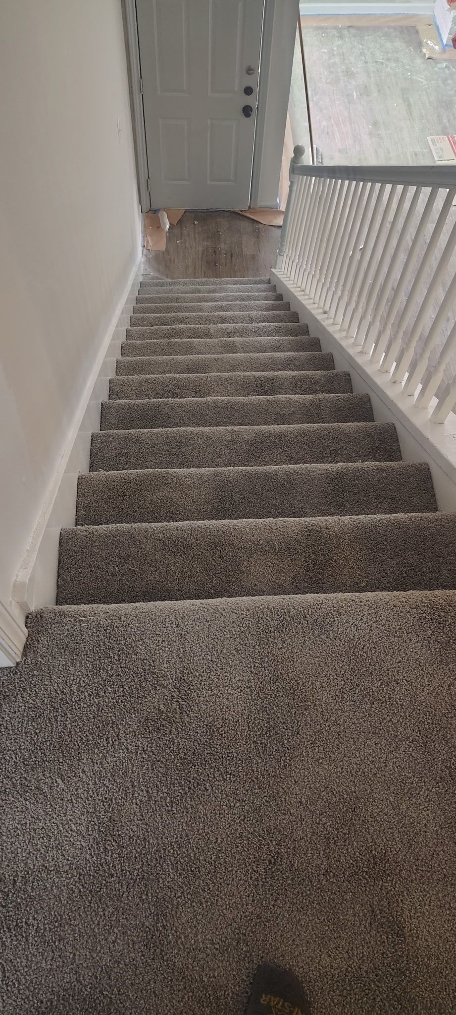 Staircase with gray carpet and white trim. White railing on the right. View from above.