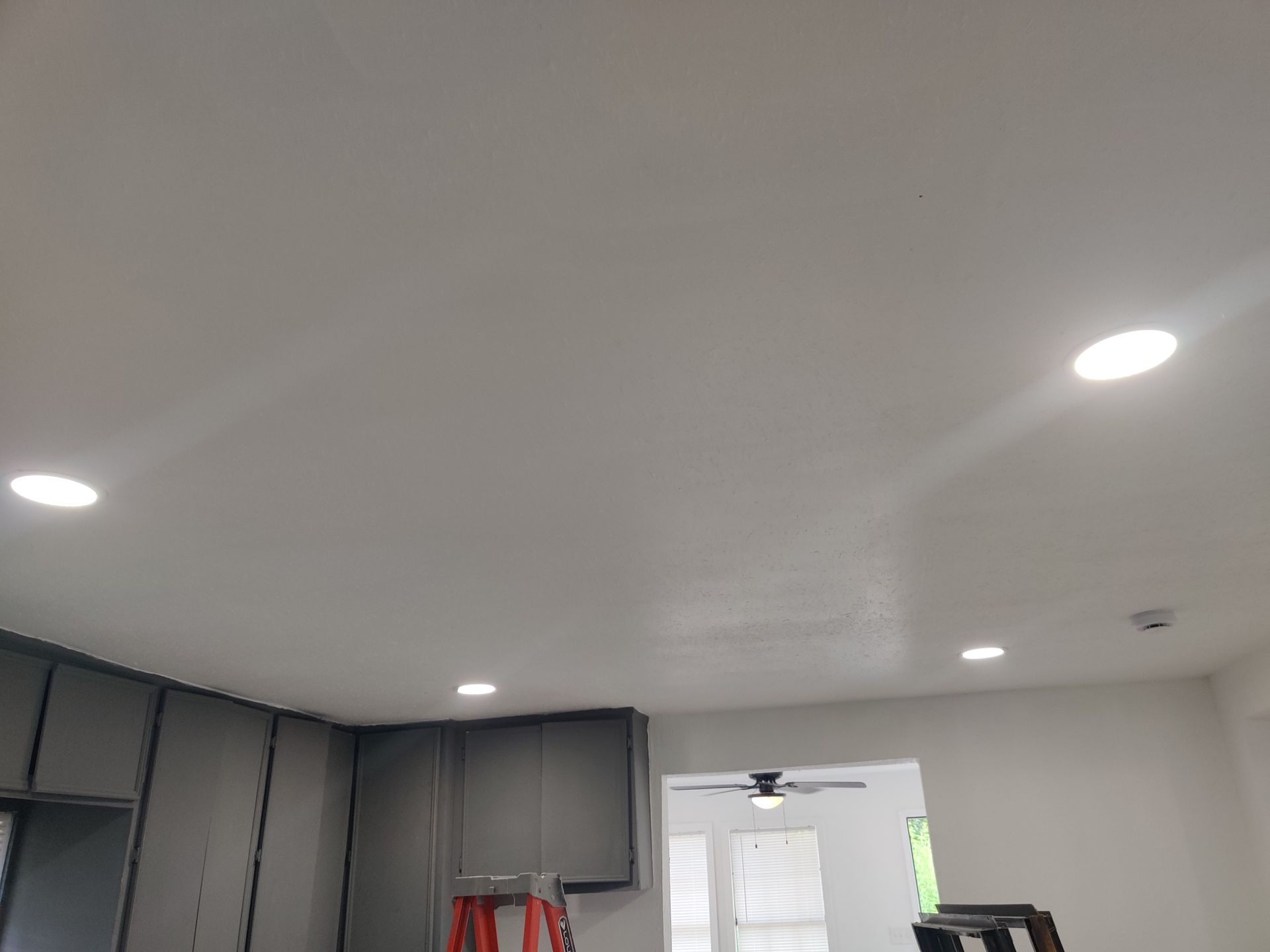 Gray cabinets, recessed lights in white ceiling, doorway to another room.