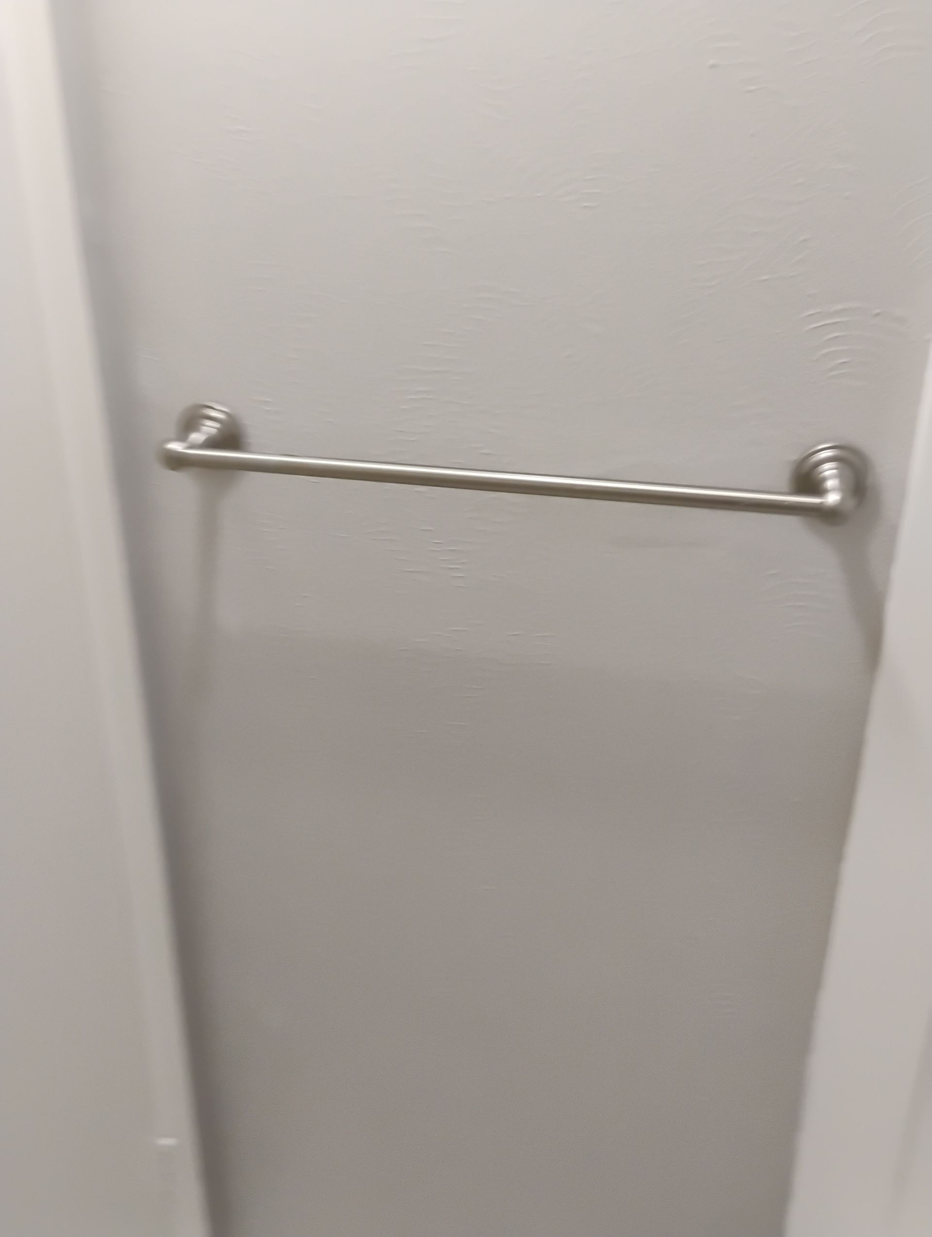 Stainless steel towel bar mounted on a gray wall between two white door frames.