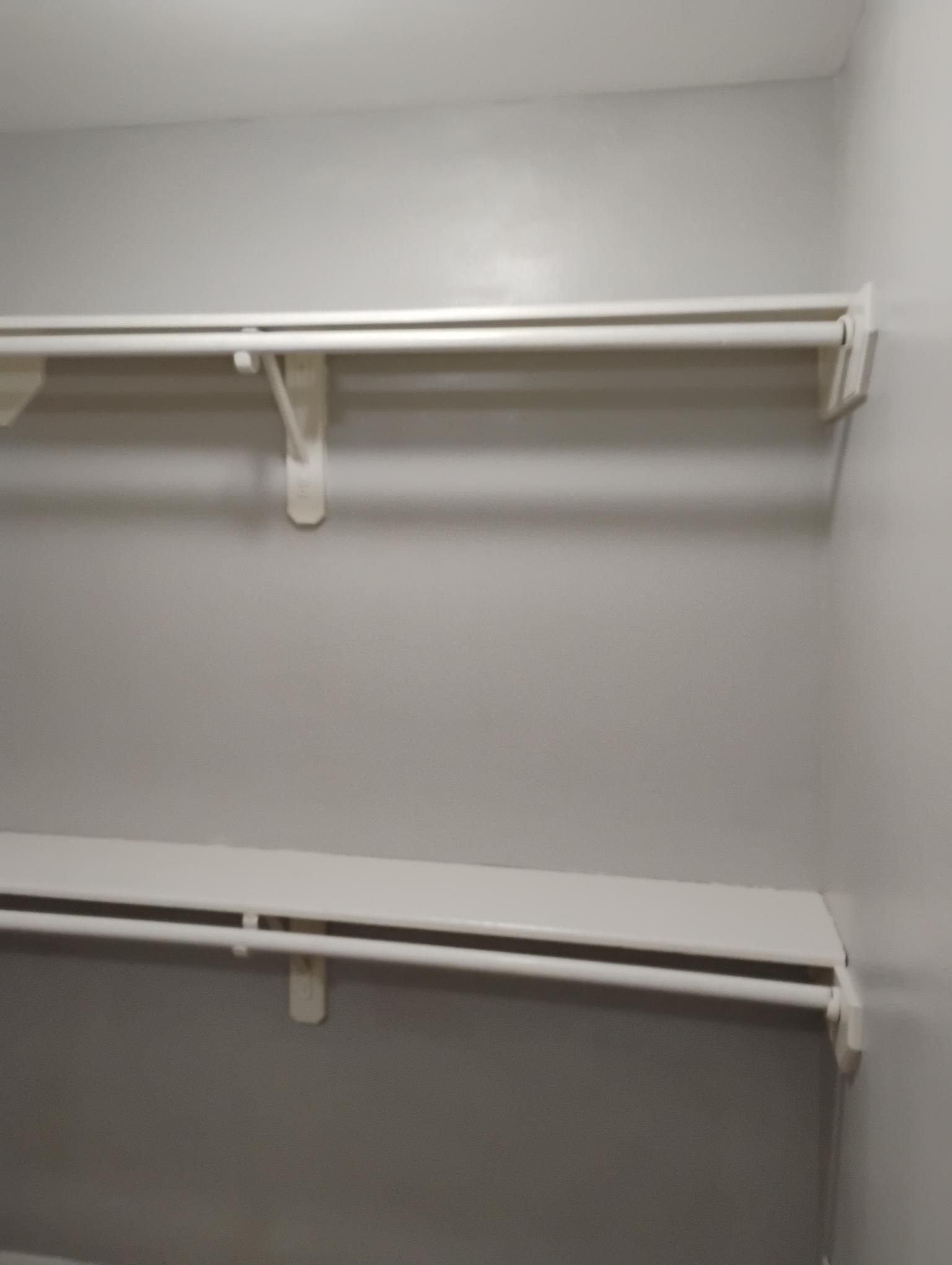 White closet shelves with a hanging rod, mounted on a gray wall.