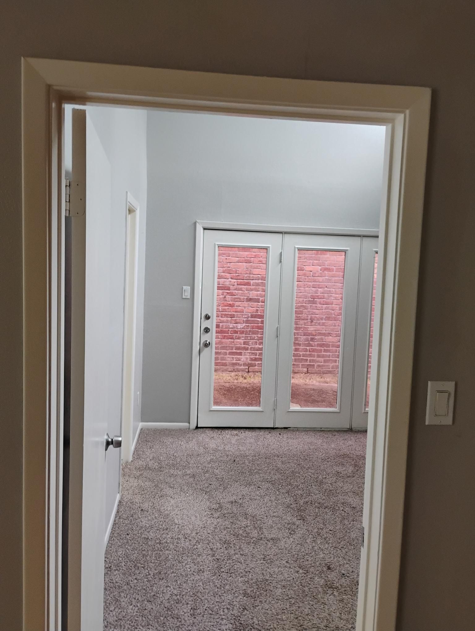 Doorway view: white trim, gray walls, carpet, French doors to brick patio.