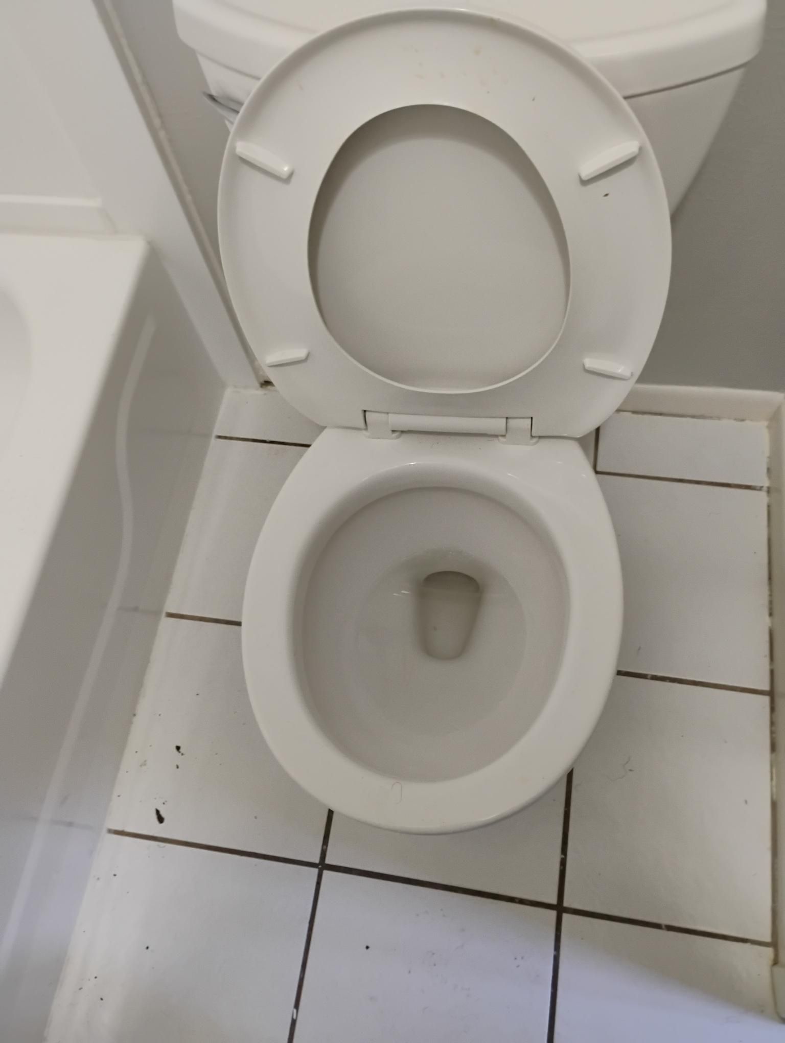 White toilet with open lid, set in a bathroom with white tile floor.