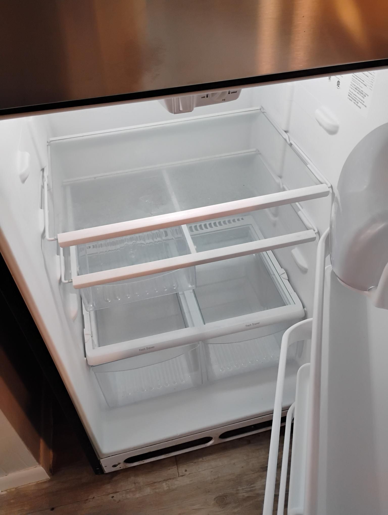Open refrigerator interior, showing three clear shelves with clear, open drawers.