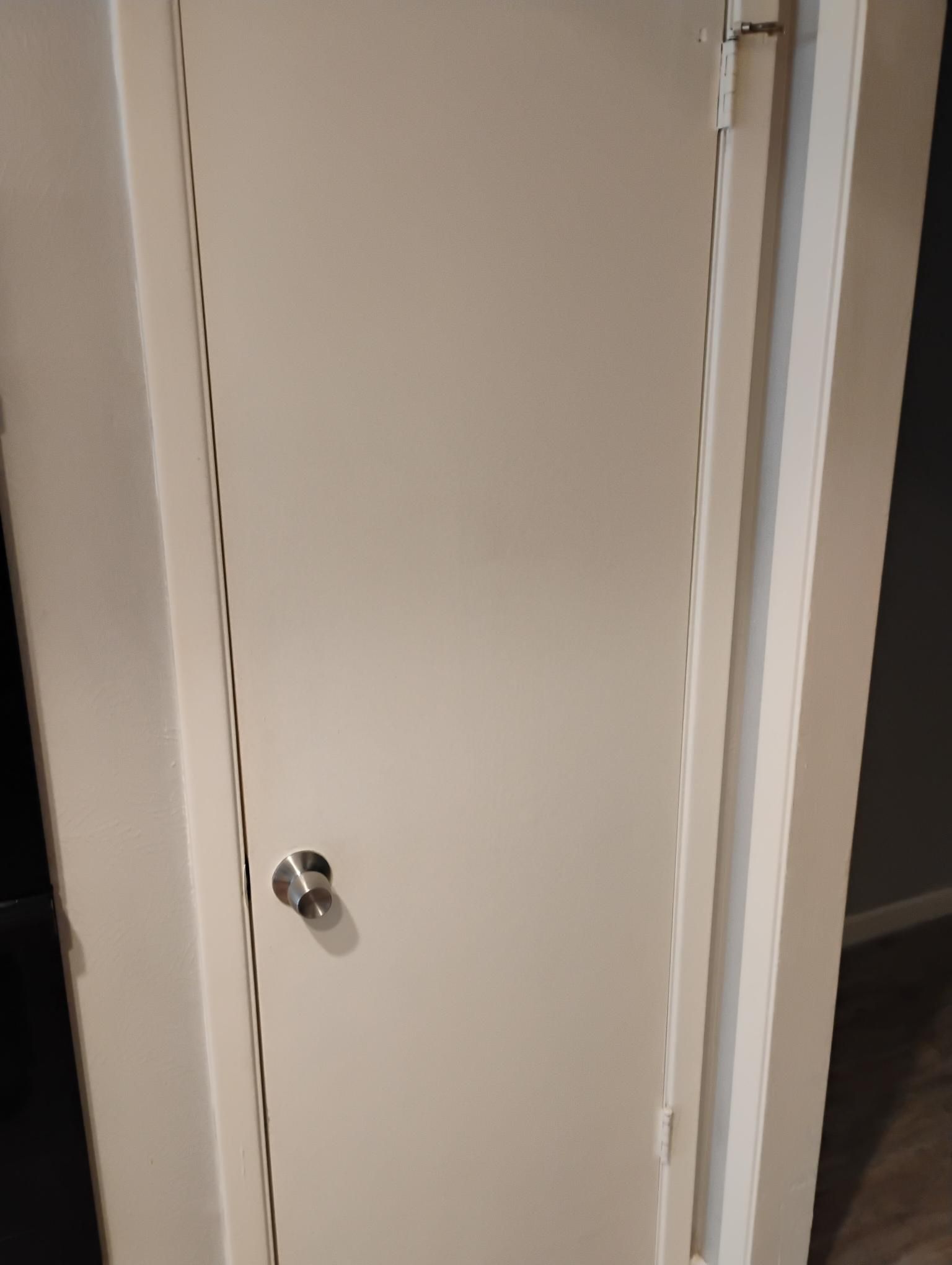 White closed door with a silver doorknob, set in a white frame against a neutral background.