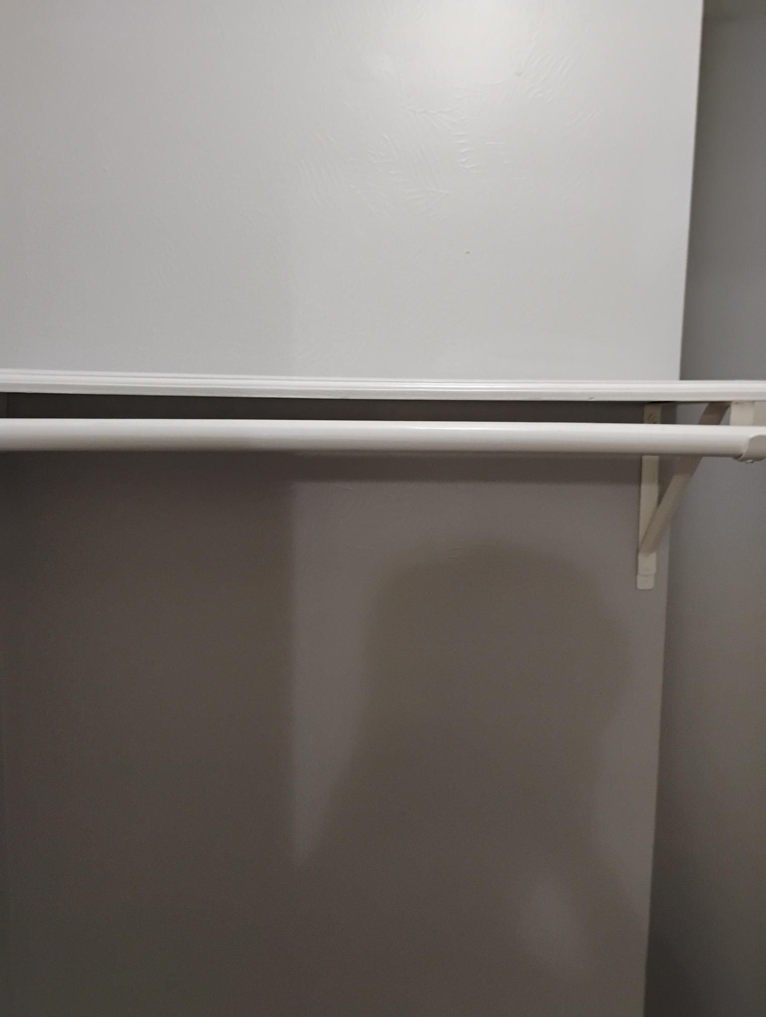 White closet shelf and clothes rod against gray painted wall.