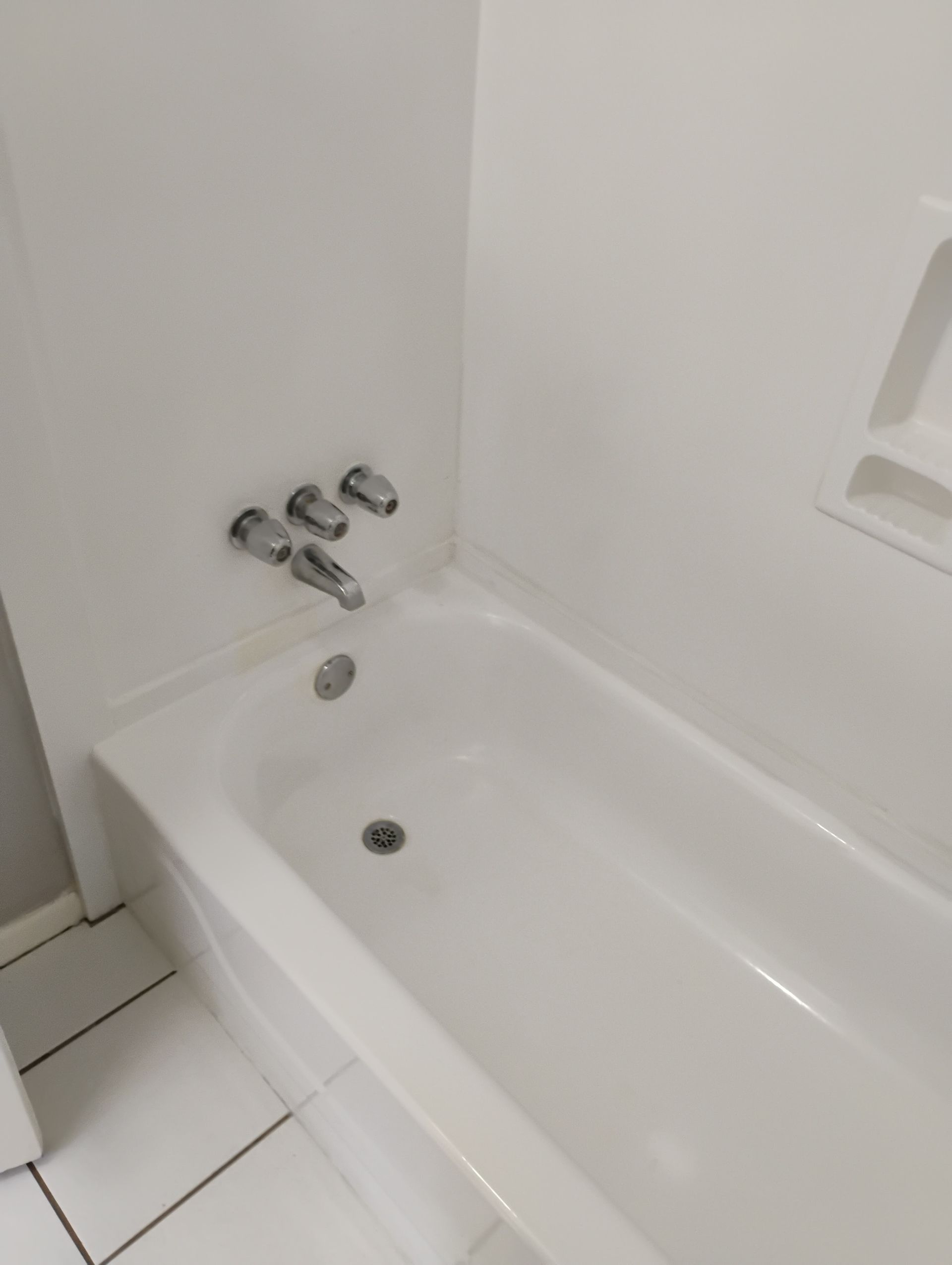 White bathtub with chrome fixtures in a white bathroom.