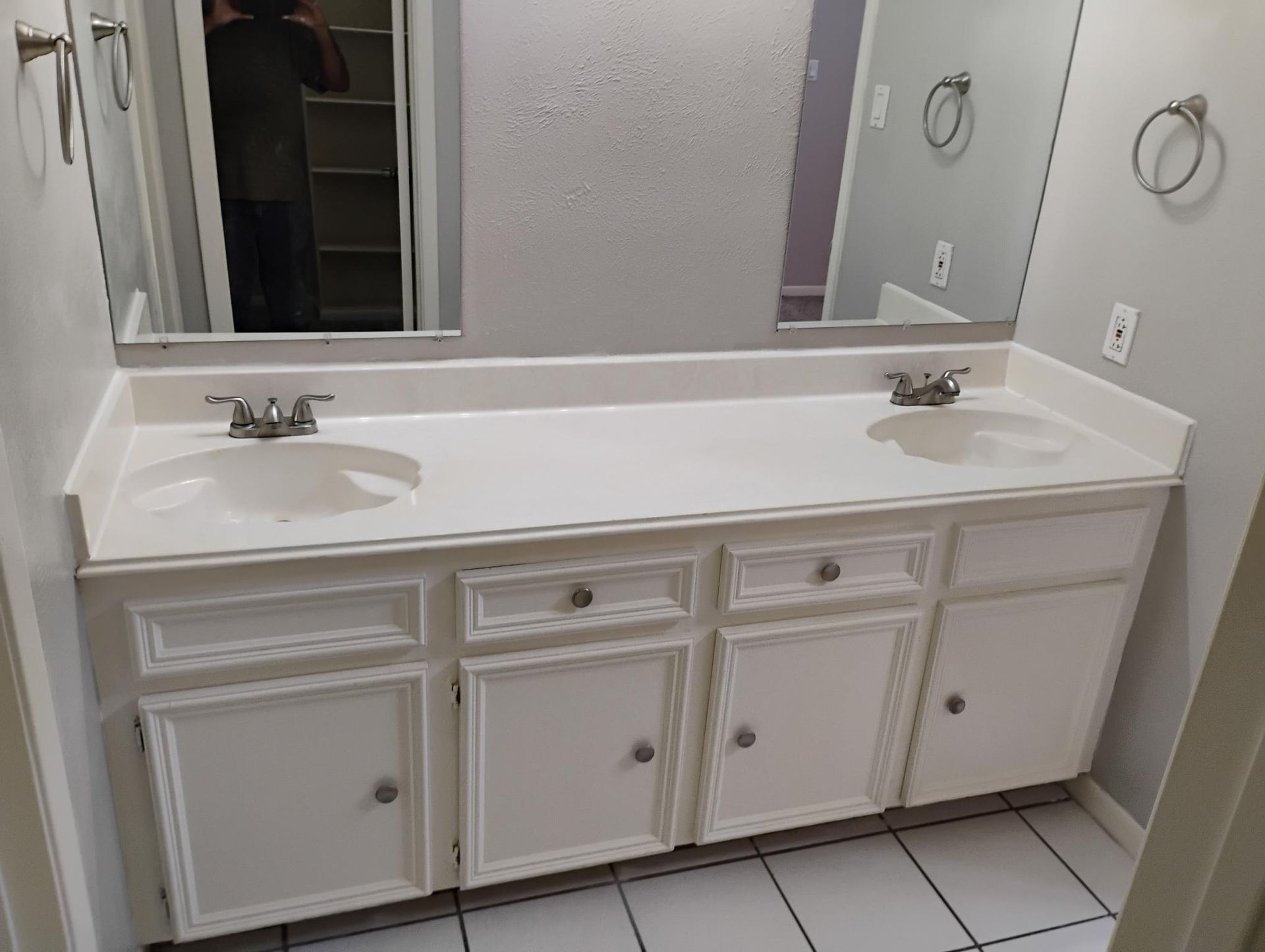 White double vanity with two sinks, gray walls, and matching mirrors in a bathroom.