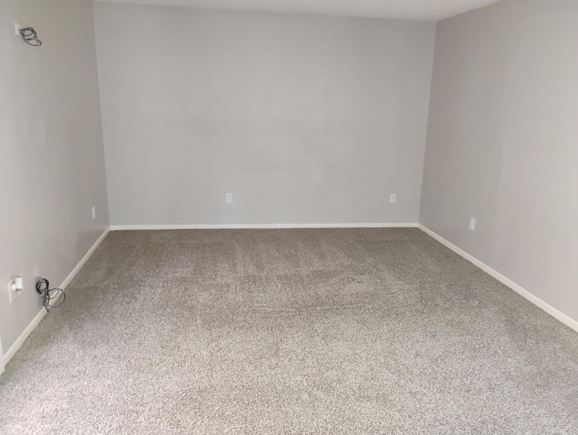 Empty room with gray walls and speckled beige carpet.