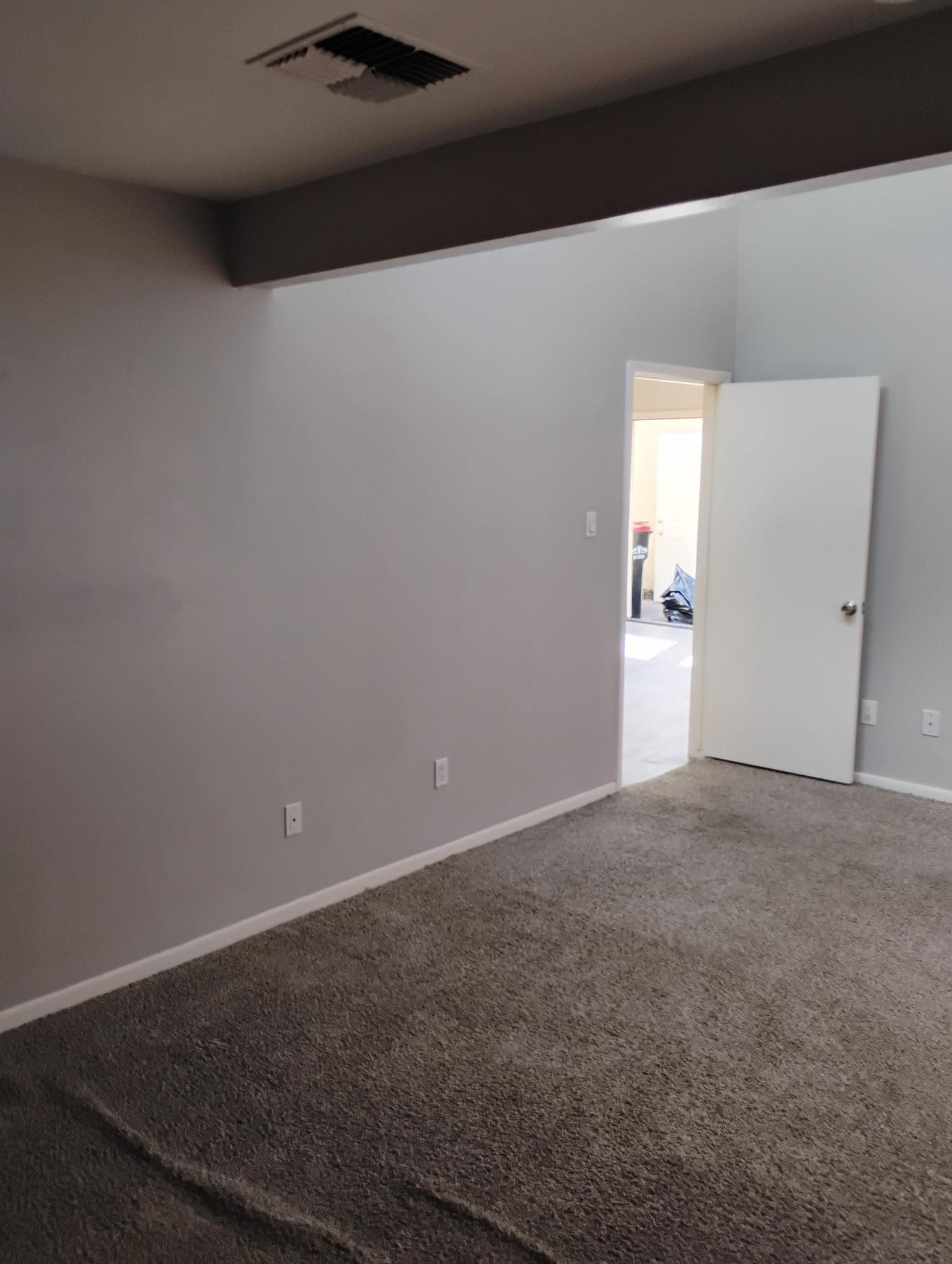 Empty room with gray walls, carpet, door, and a recessed ceiling fixture.