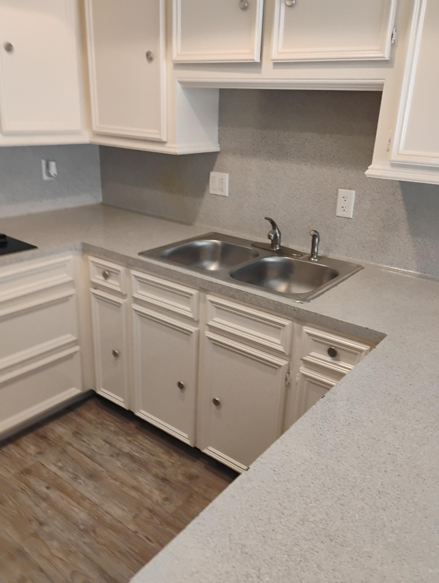 Kitchen with white cabinets, light gray countertops, and stainless steel sink.