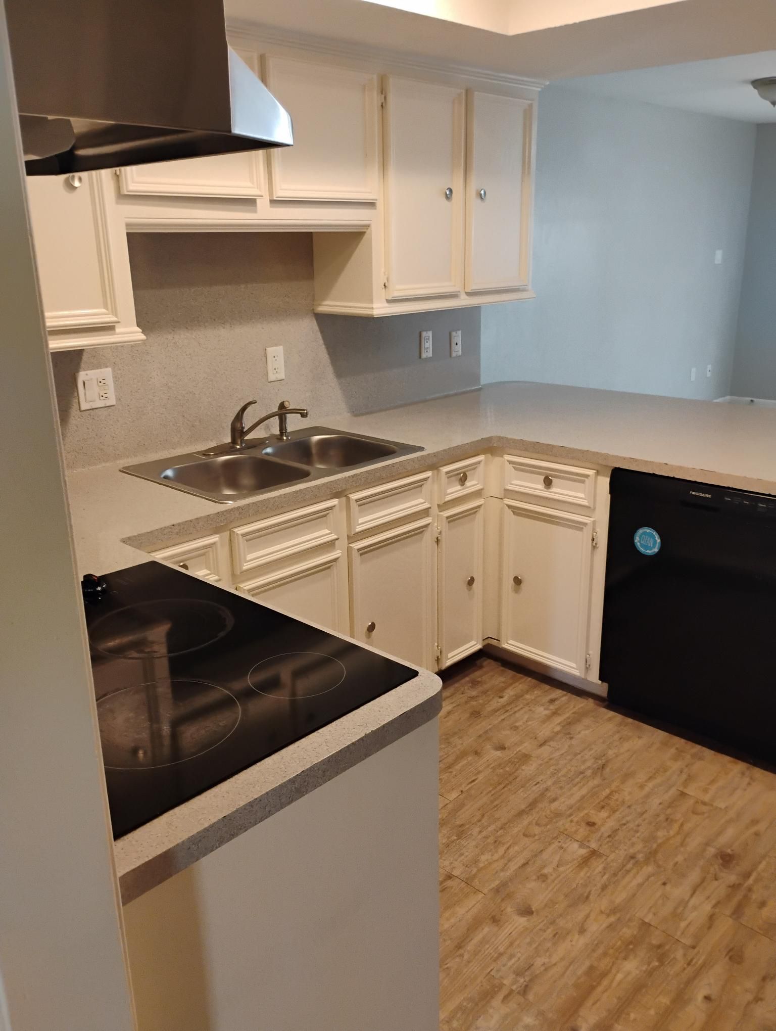 White kitchen cabinets and countertops with black appliances and stovetop.