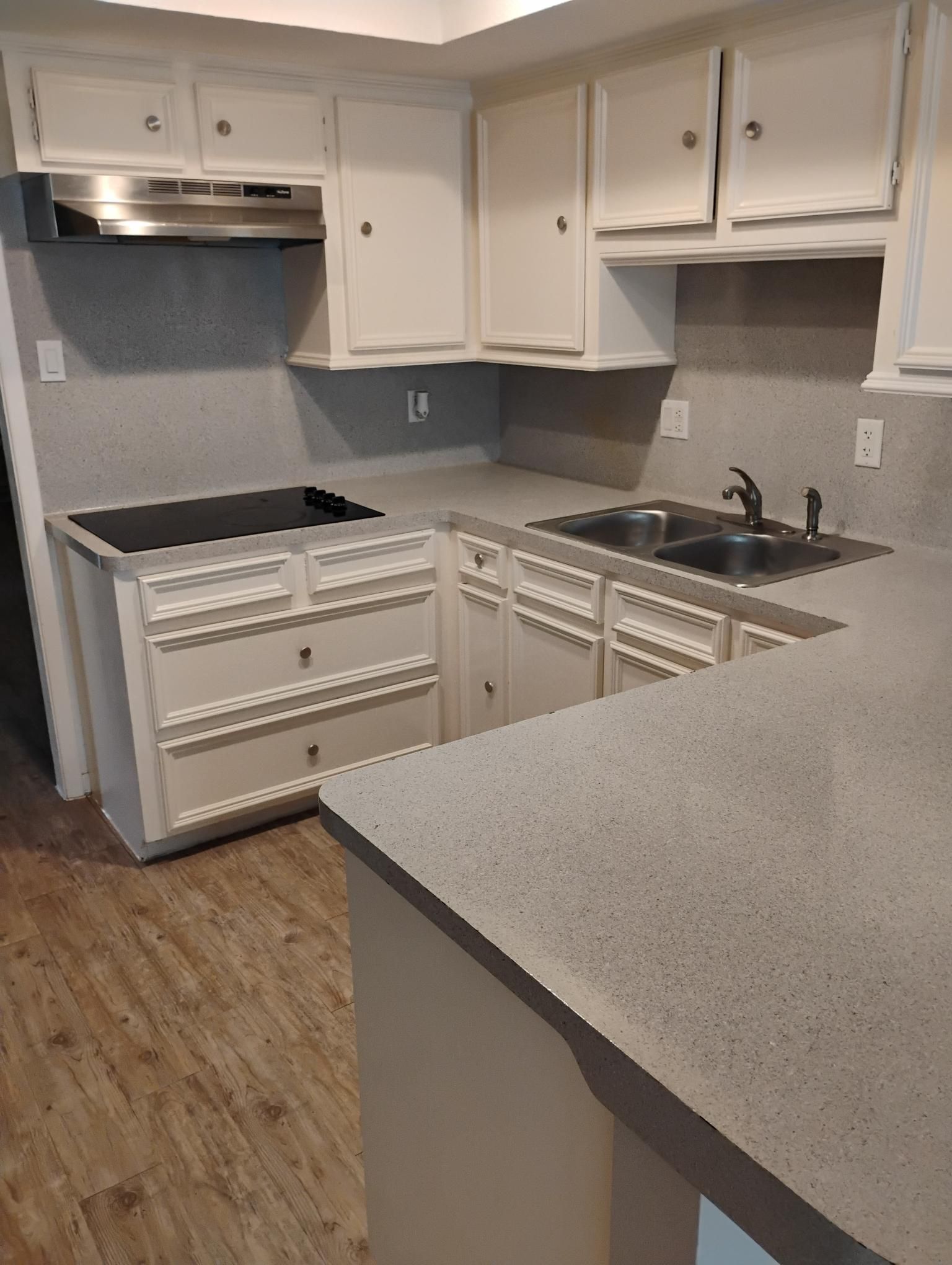 White kitchen cabinets and countertops with a stainless steel range hood.