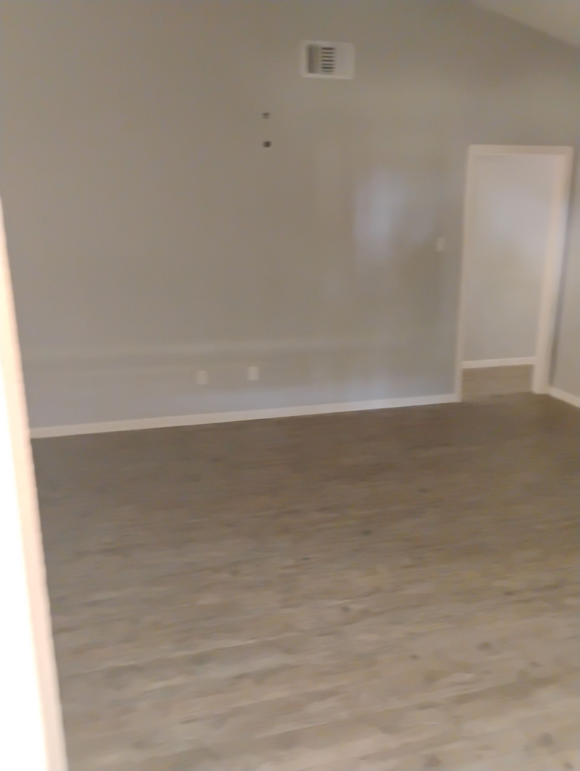 Empty room with gray walls and wood-look flooring. Light coming through doorway.