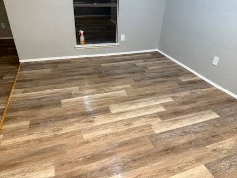 Room with wood-look flooring and gray walls, a window, and baseboards.