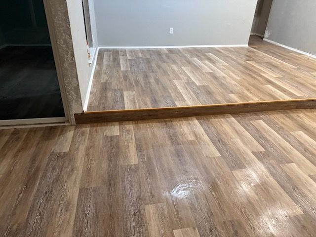 Newly installed wood-look laminate flooring in a room with a raised platform.