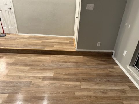 A room with wood-look flooring and a raised area; gray walls, white trim and doors.