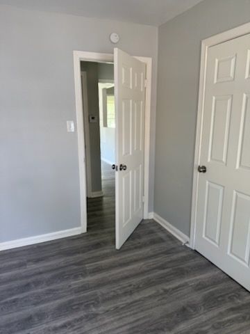 A room with gray walls and flooring, two white doors, one open to a hallway.