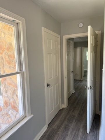 Narrow hallway with three white doors, grey walls, and a window with stone detail.