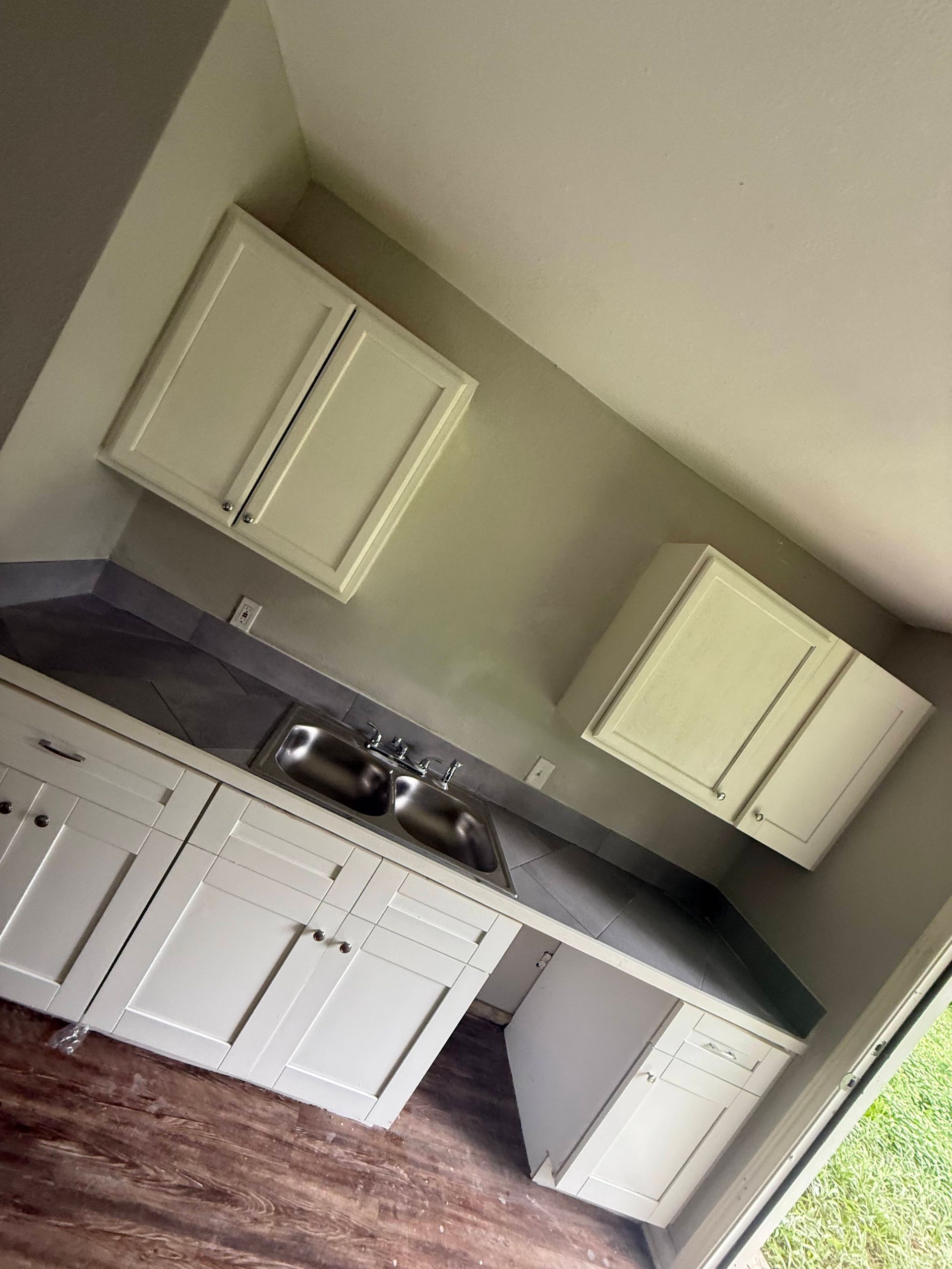 White kitchen cabinets with gray countertops and stainless steel sink.
