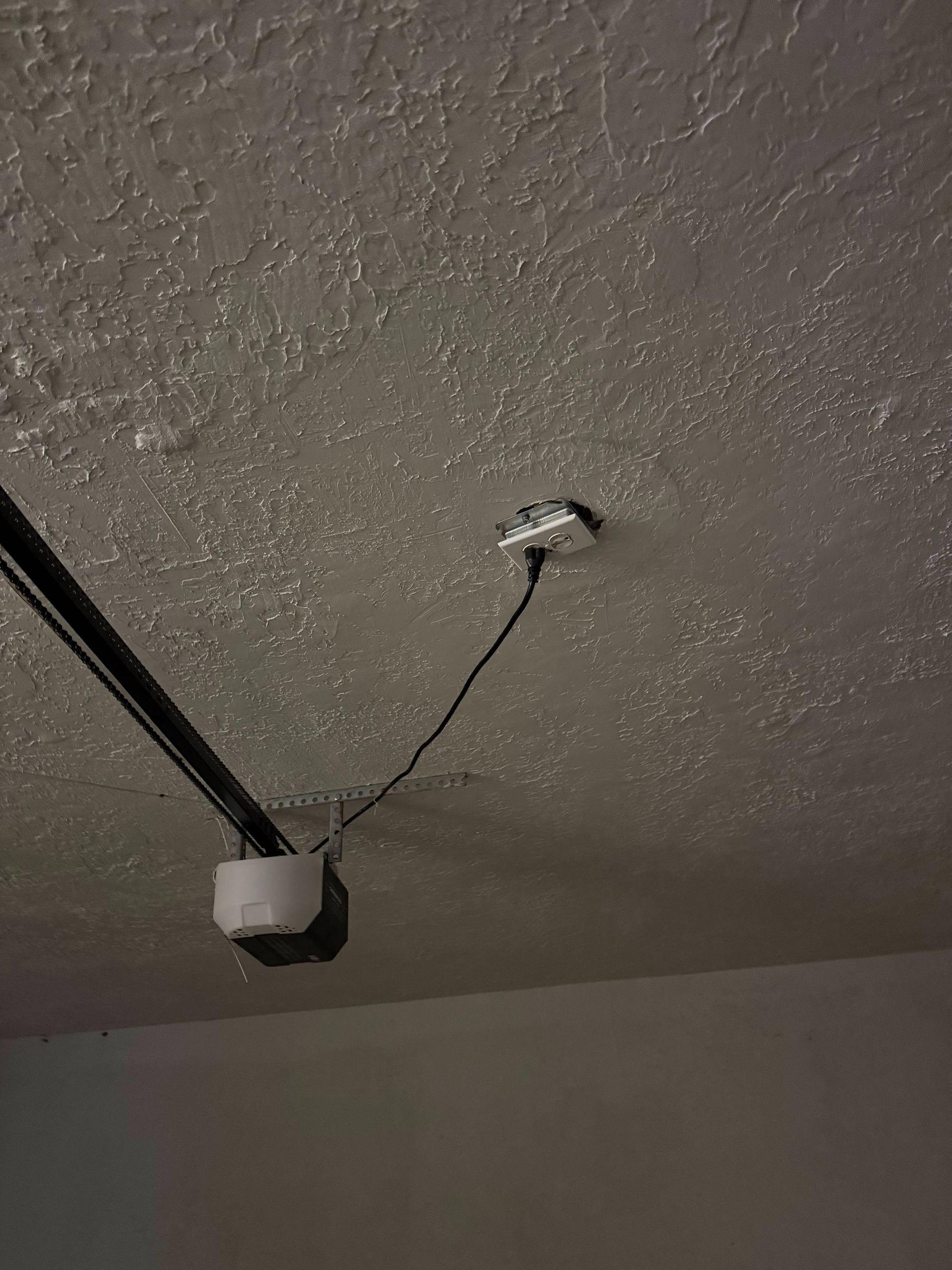 Ceiling with two electrical boxes and wiring. One box is white, the other is open, with a wire attached.
