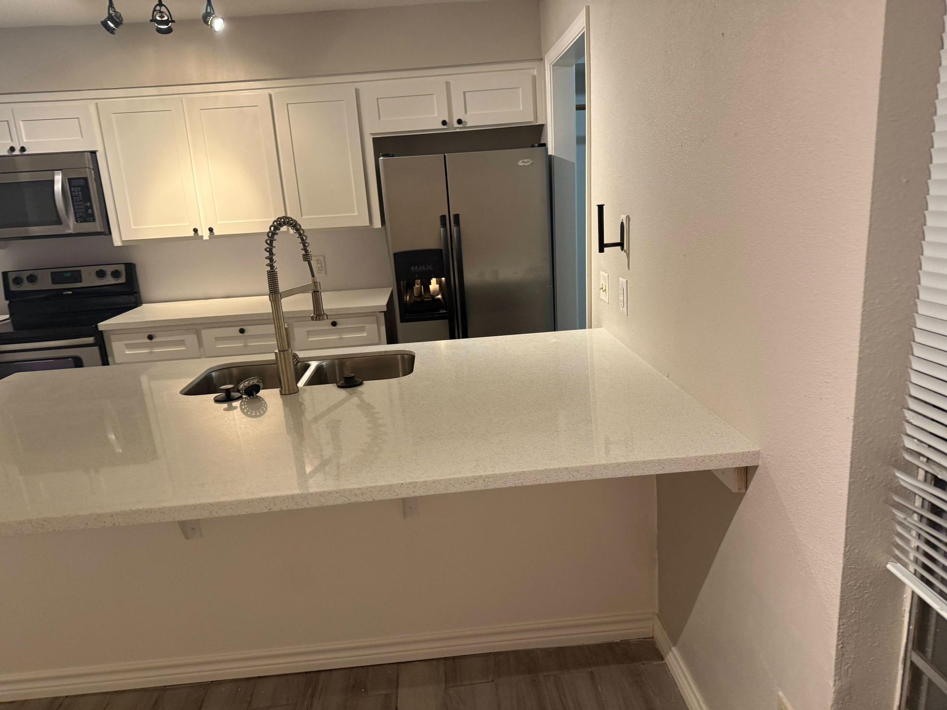 Kitchen with white cabinets, light countertops, and stainless steel appliances.