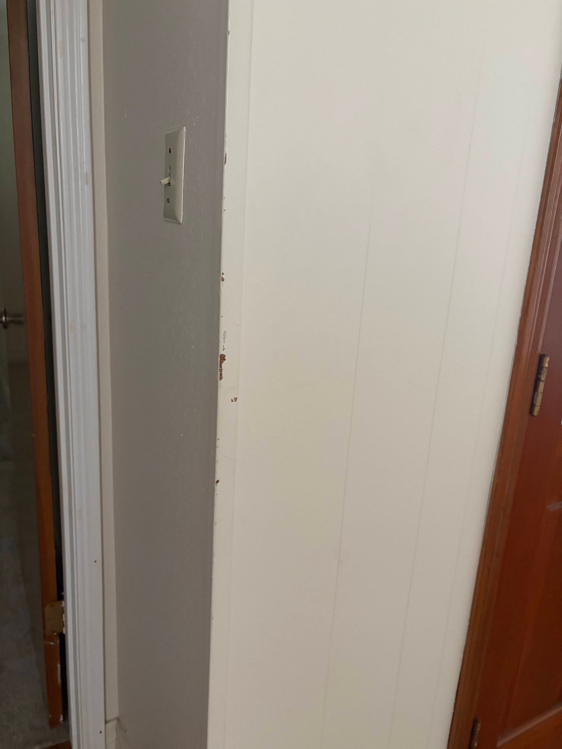 Narrow hallway with off-white walls. A door on each side. A light switch is visible on one wall.