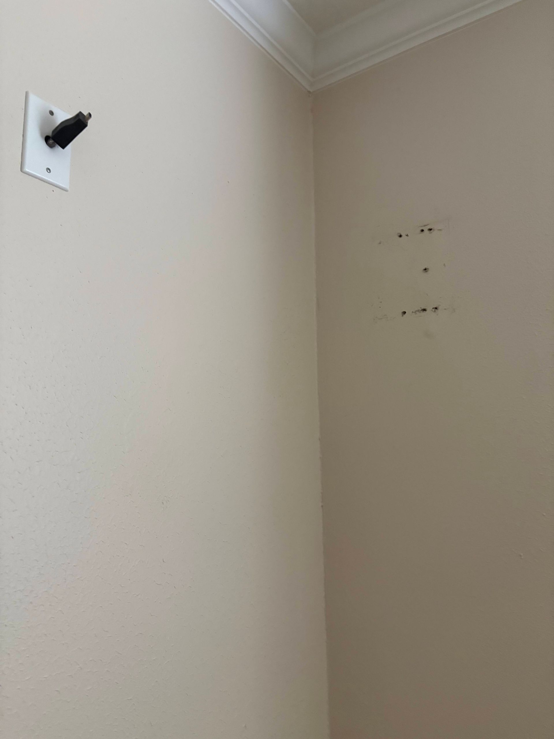 Beige walls with mounting hardware and marks from an item removal. White trim at the top.