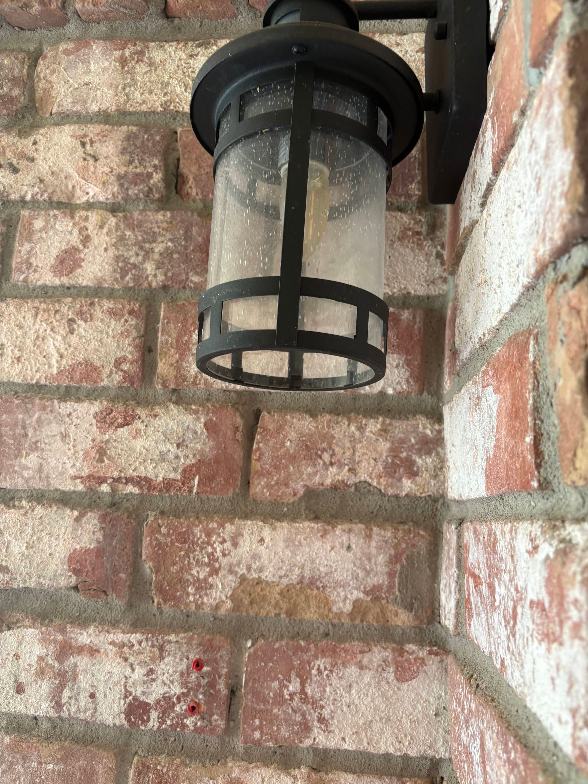 Outdoor lantern on red brick wall.