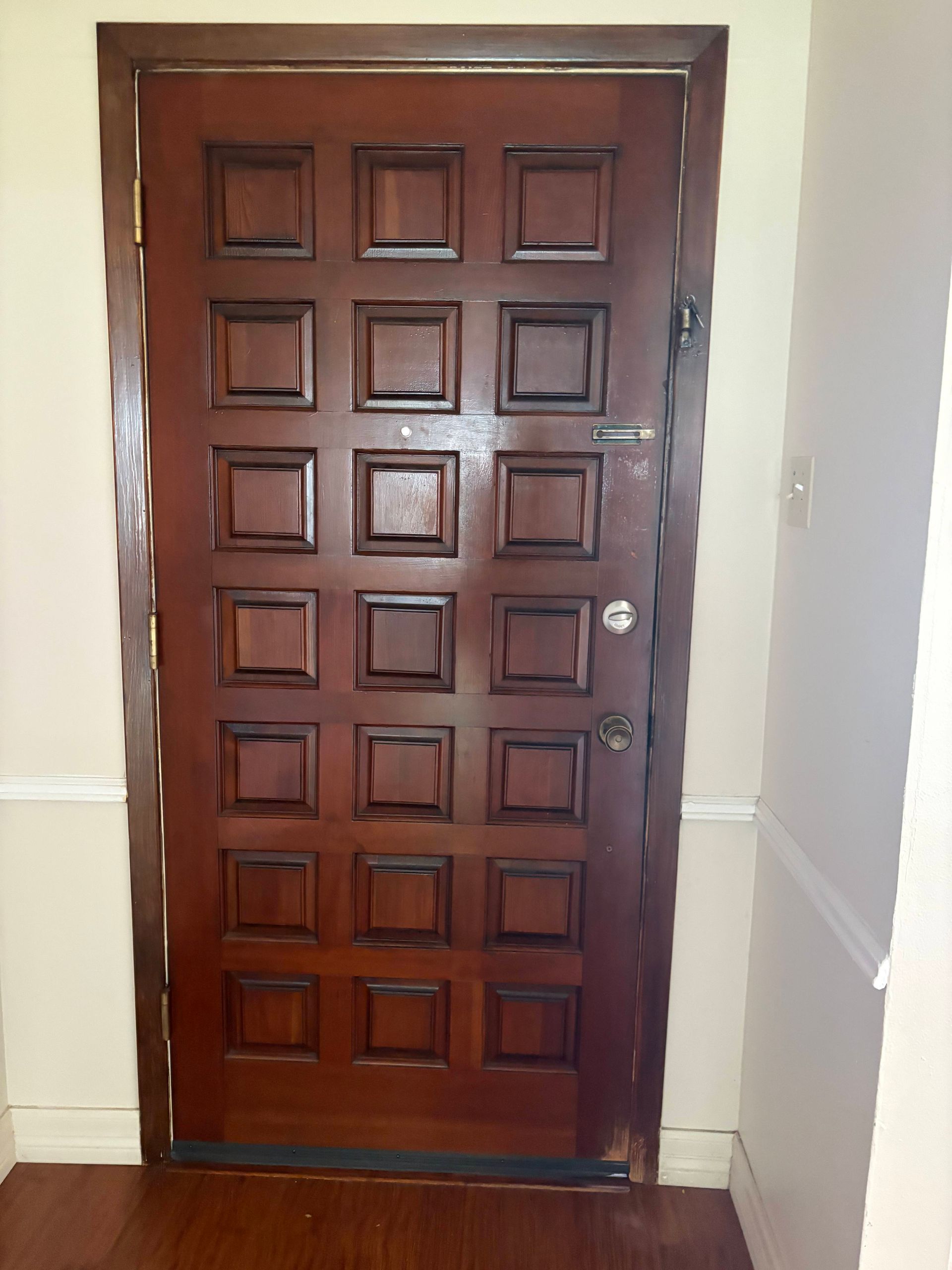 Brown wooden door with square panels in a hallway.