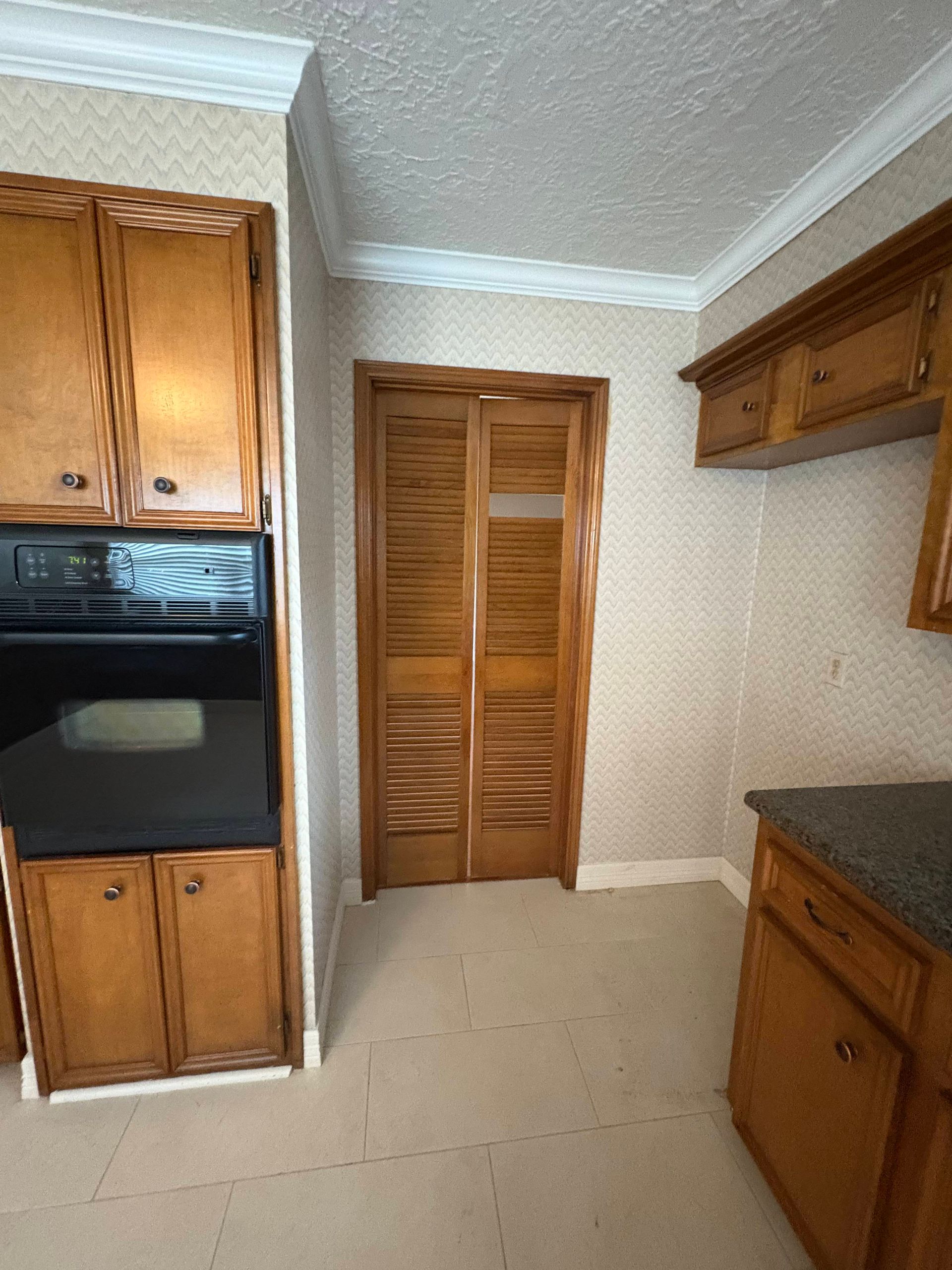 Kitchen with wood cabinets, black oven, and shuttered door.