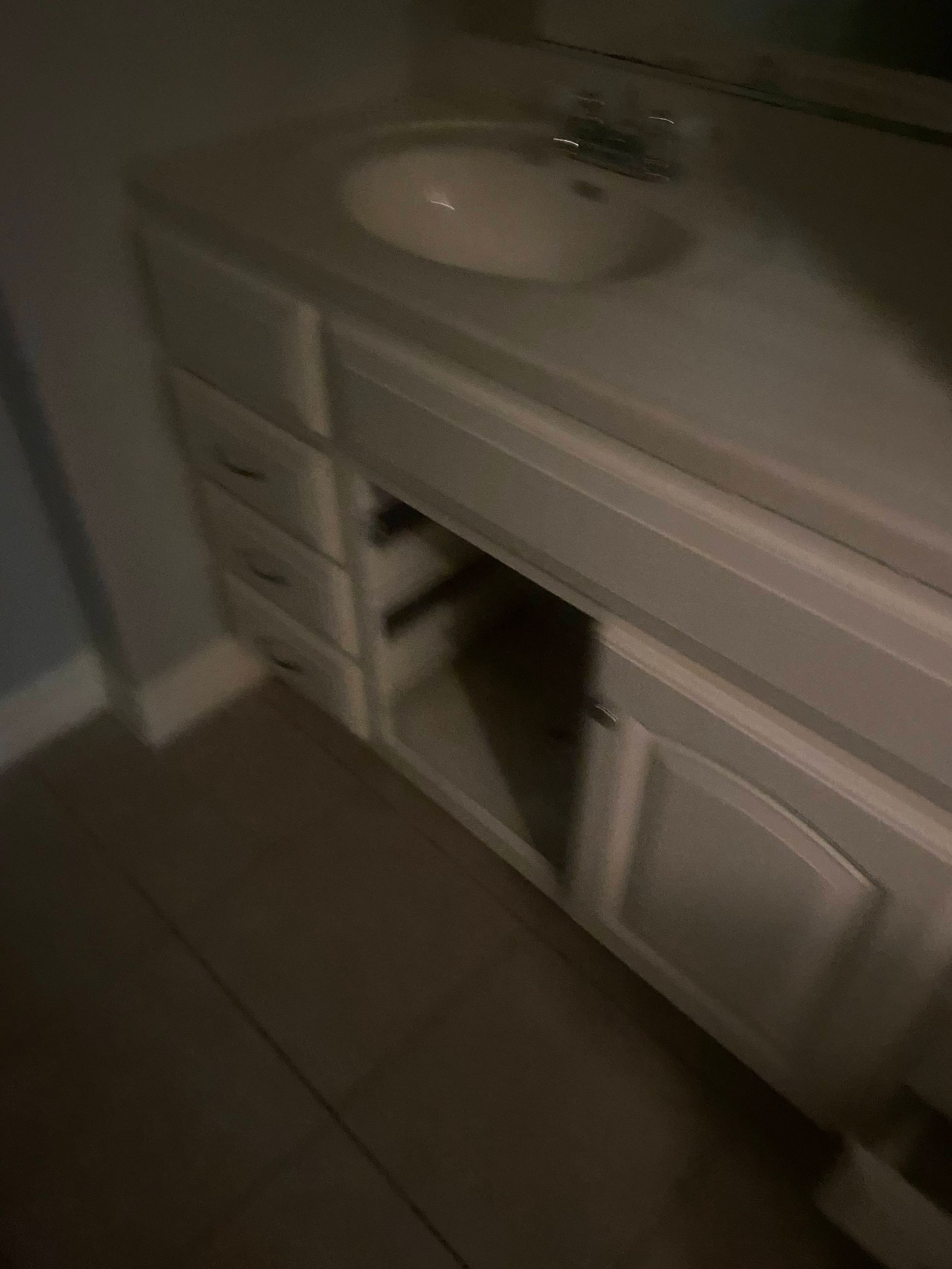 Bathroom vanity with white cabinet, sink, and drawers.