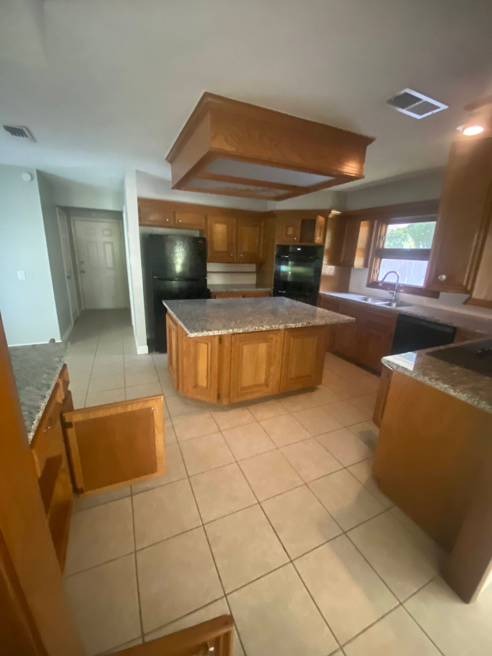 Kitchen with wood cabinets, island, and granite countertops.