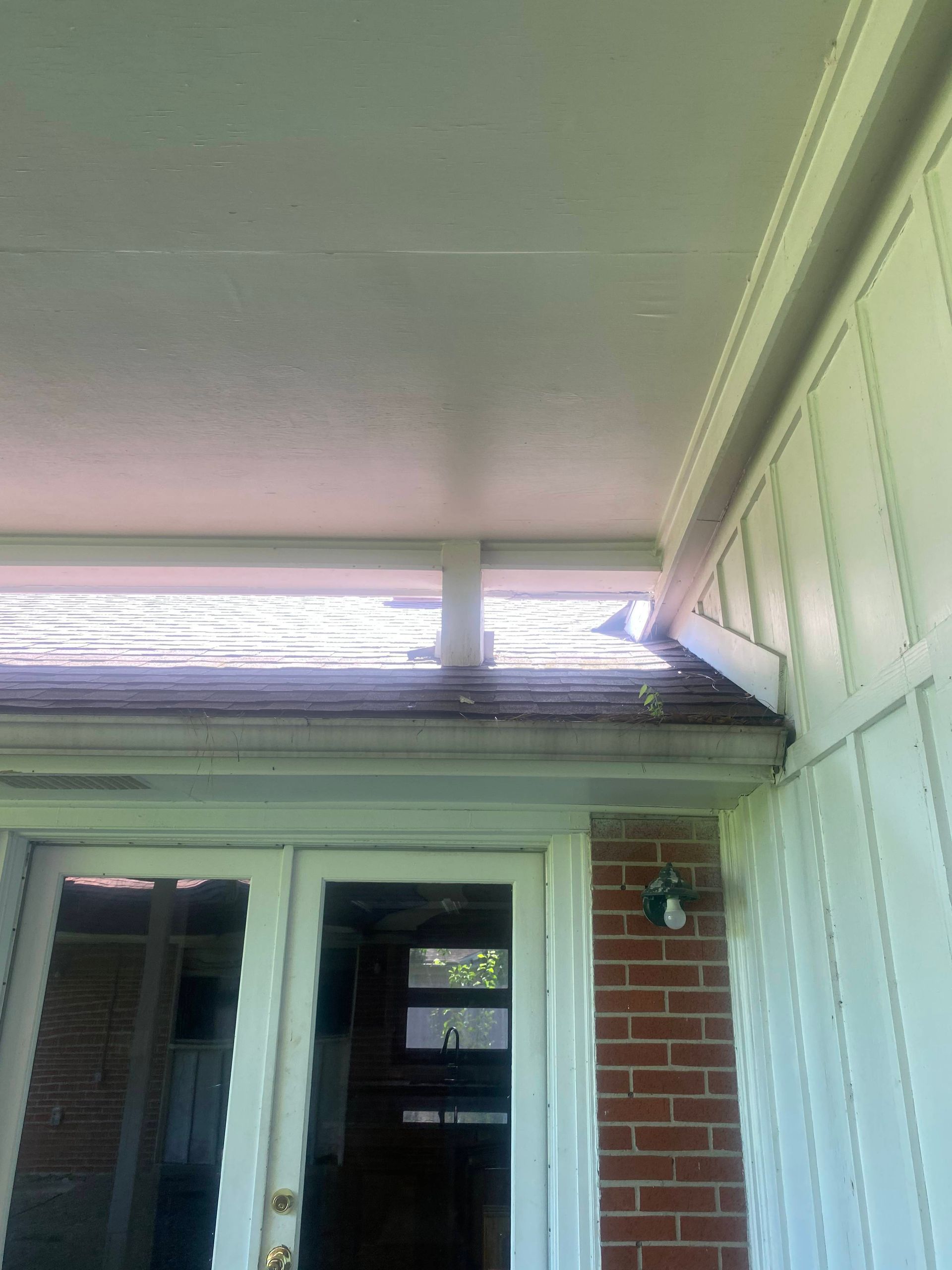 White ceiling over exterior door, window, and brick wall.