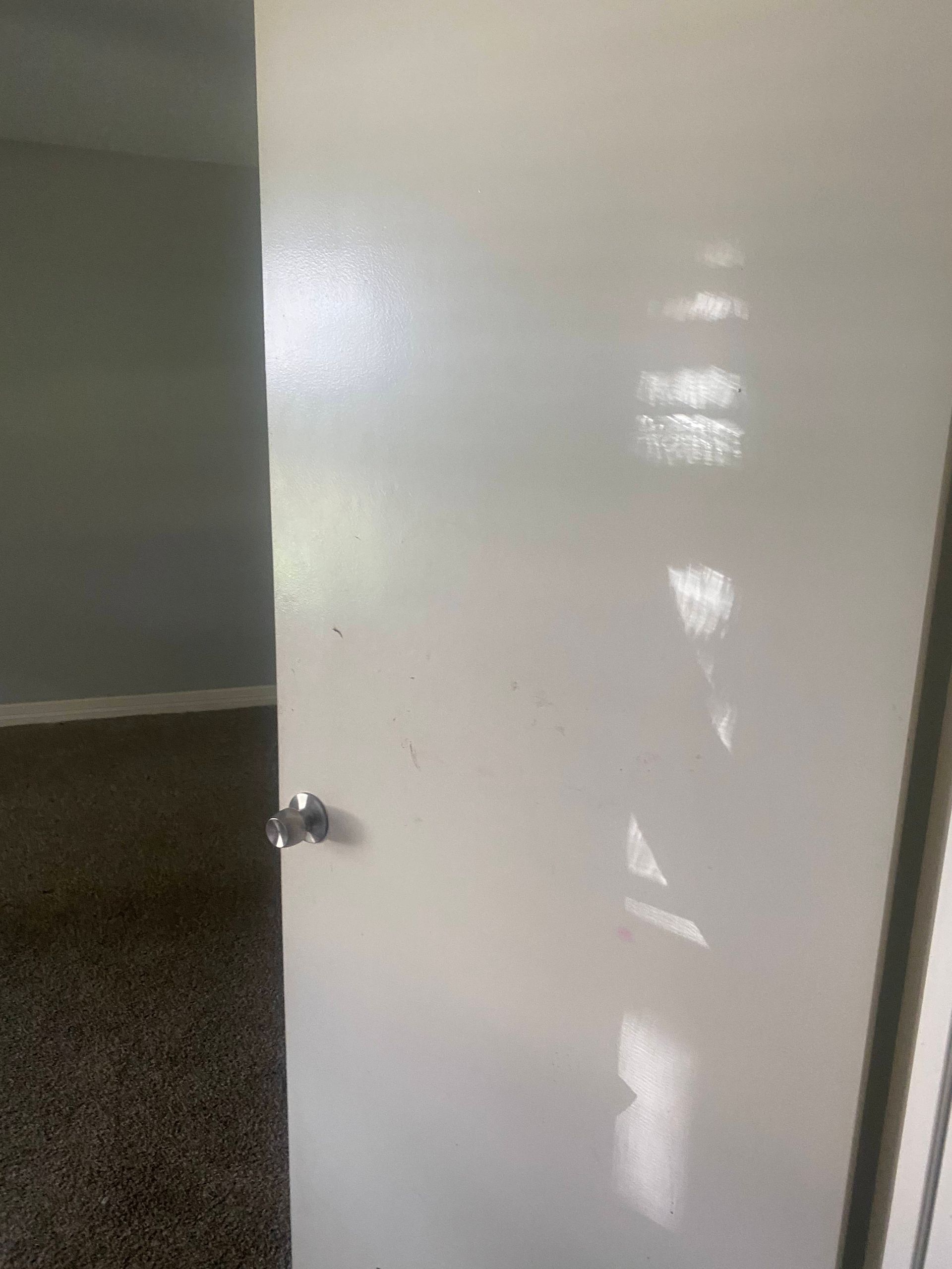 White door partially open to a room with carpet and gray walls.