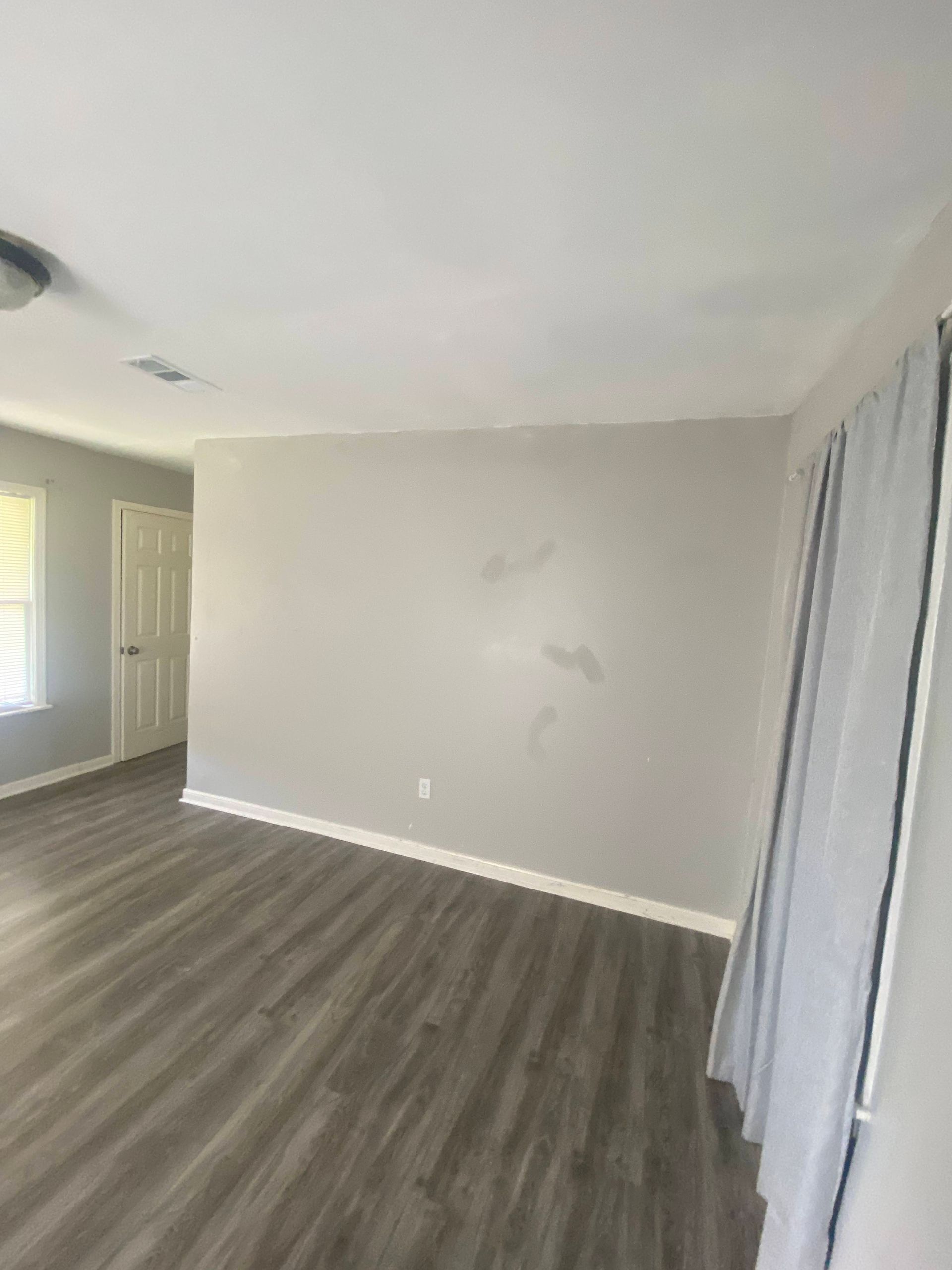 Empty room with gray walls and flooring, white ceiling, and a white door in the distance.