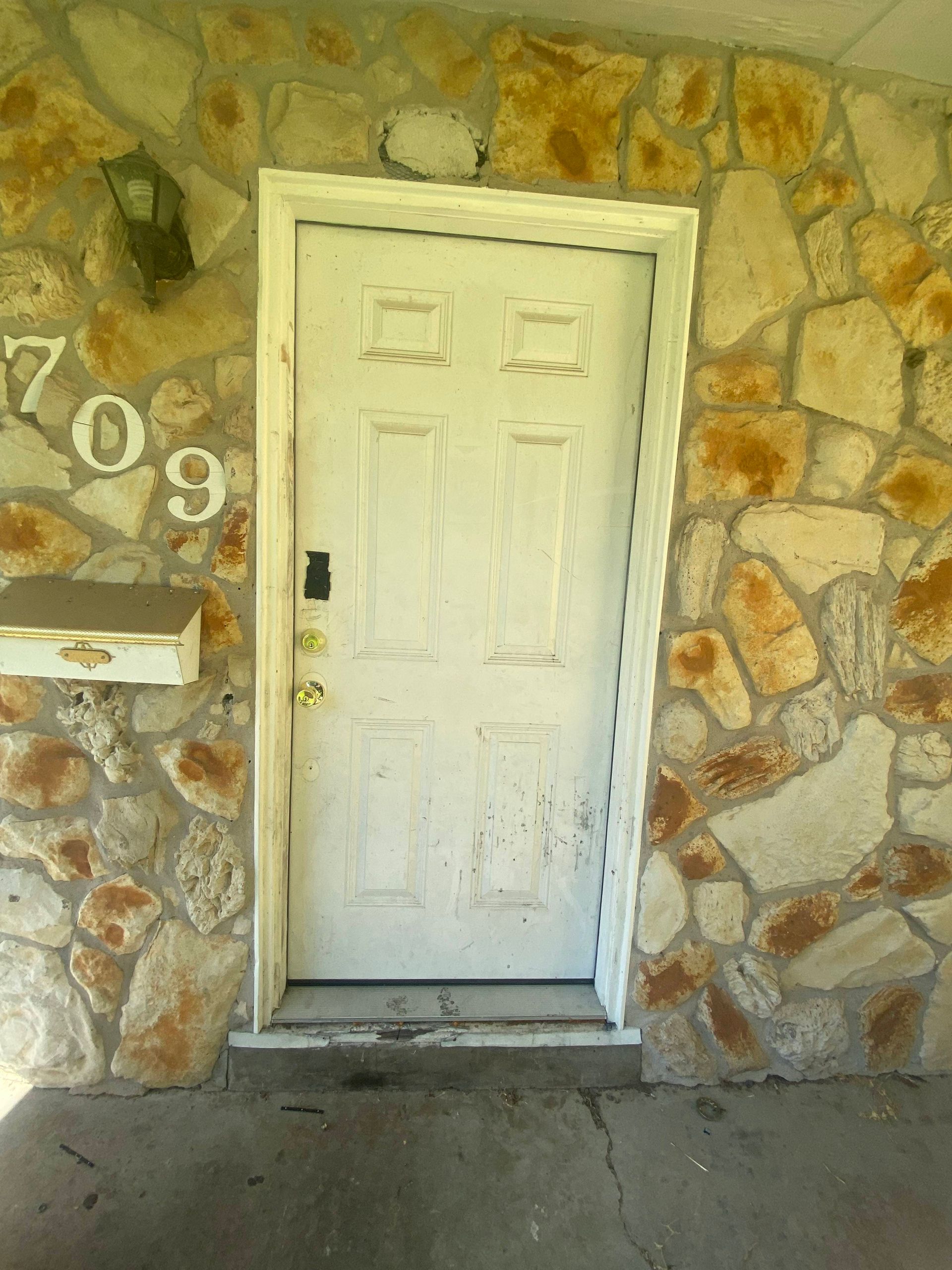 White door with visible wear in a stone facade doorway, number 709 visible.