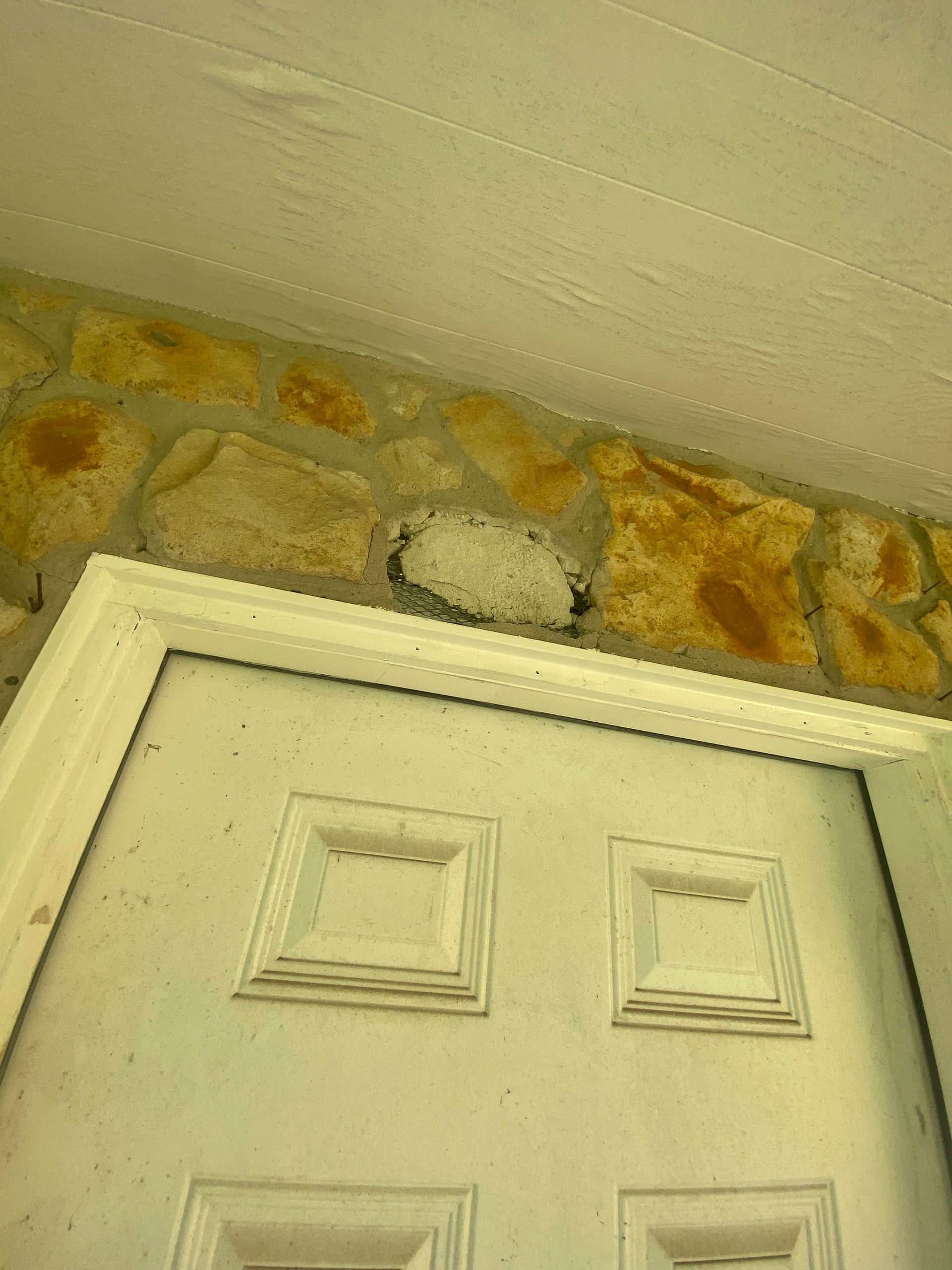White door beneath stone wall and off-white ceiling.