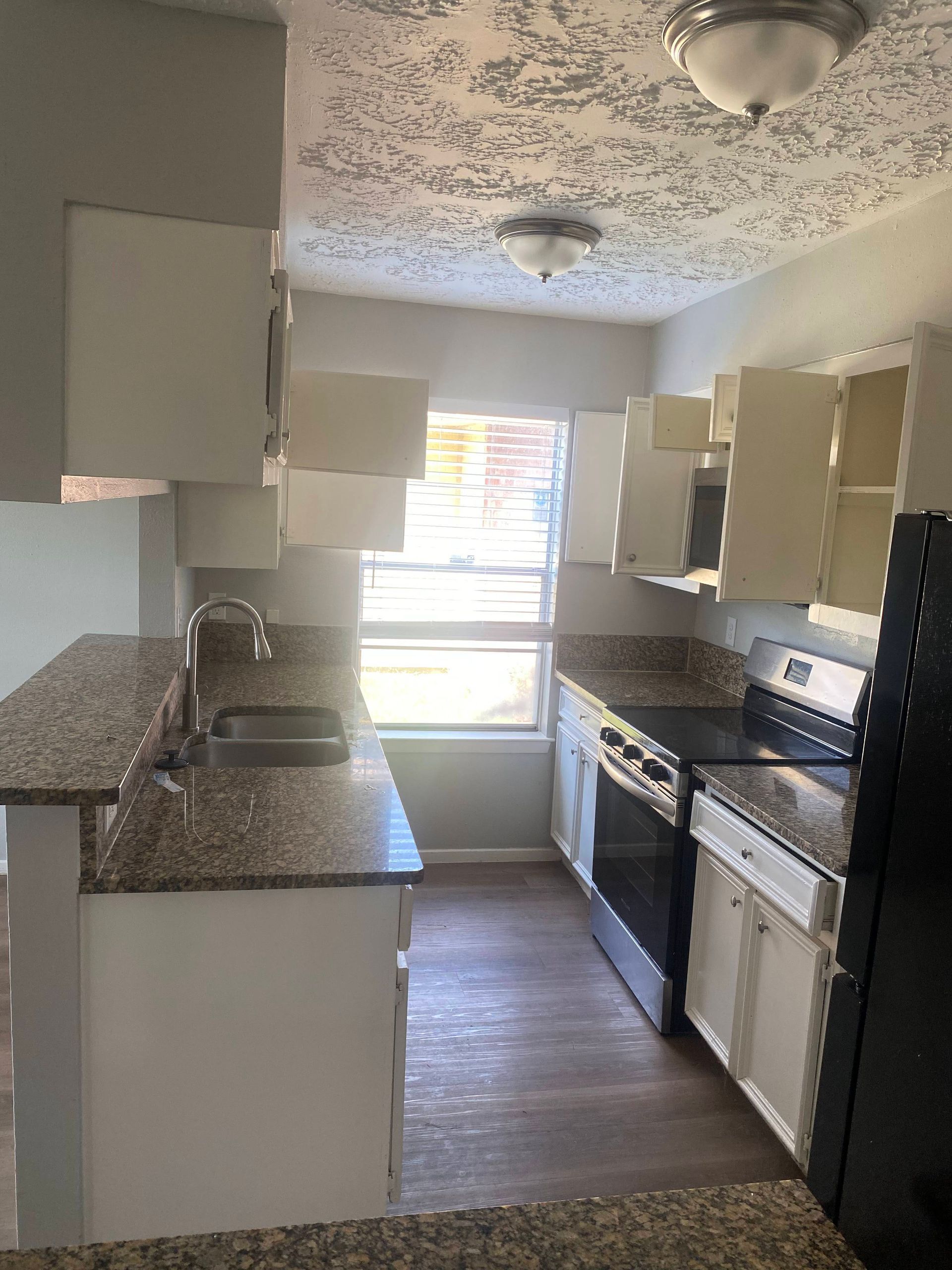 Kitchen with white cabinets, granite countertops, and a window.
