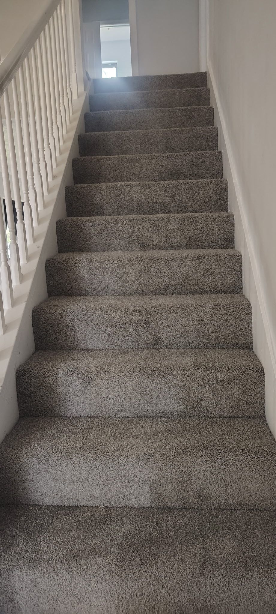 Staircase with carpeted steps and a white railing on the left side, leading upward.